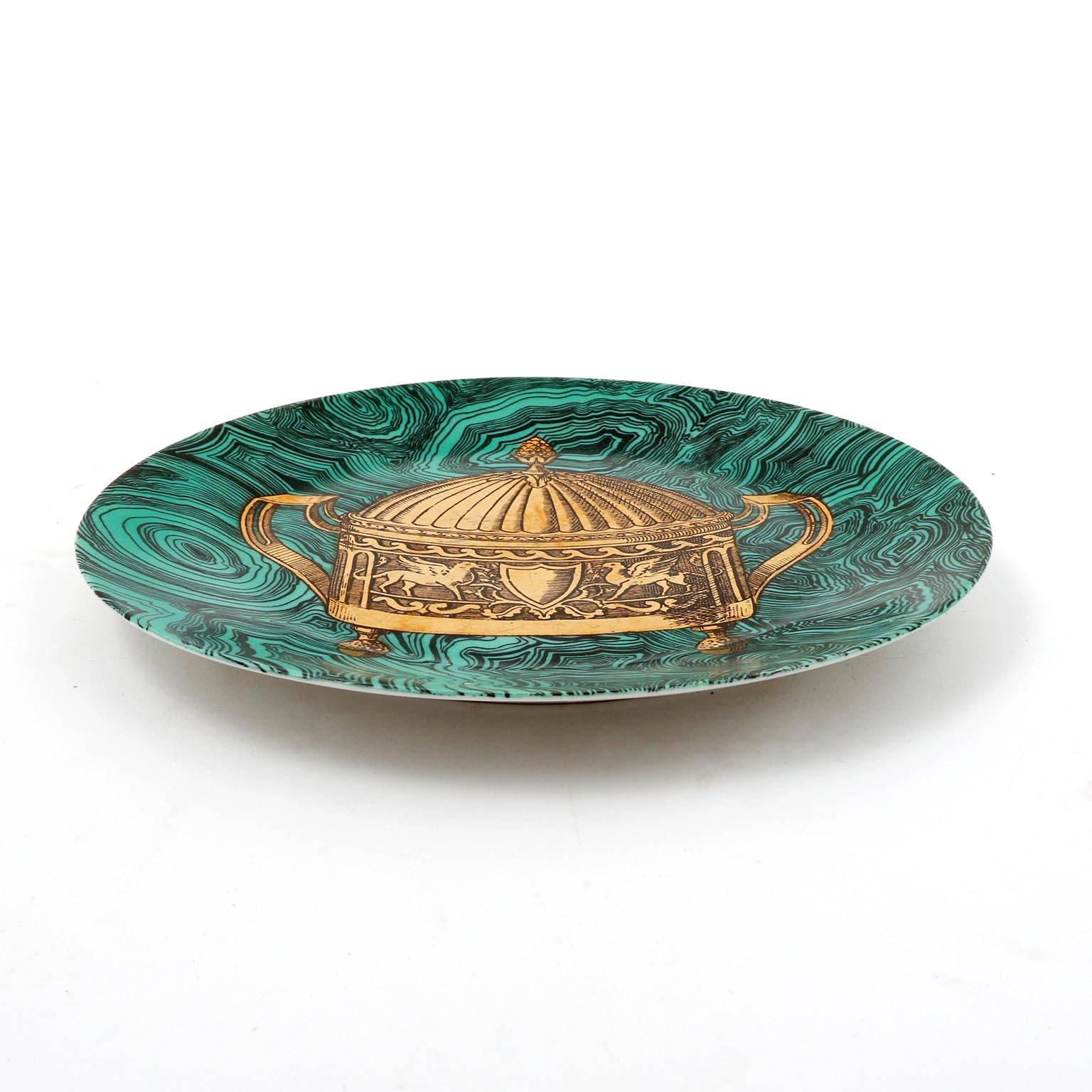 A ceramic or porcelain dish with an emerald green faux malachite ground and painted in gold by Piero Fornasetti, Italy, manufactured in Mid-Century in 1950s. 
This hand-colored decorative plate is one in a series of ‘faux malachite’ designs that