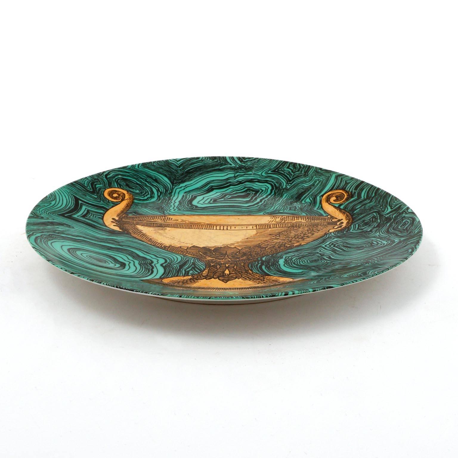 A ceramic or porcelain dish with an emerald green faux malachite ground and painted in gold by Piero Fornasetti, Italy, manufactured in Mid-Century in 1950s. 
This hand-colored decorative plate is one in a series of ‘faux malachite’ designs that