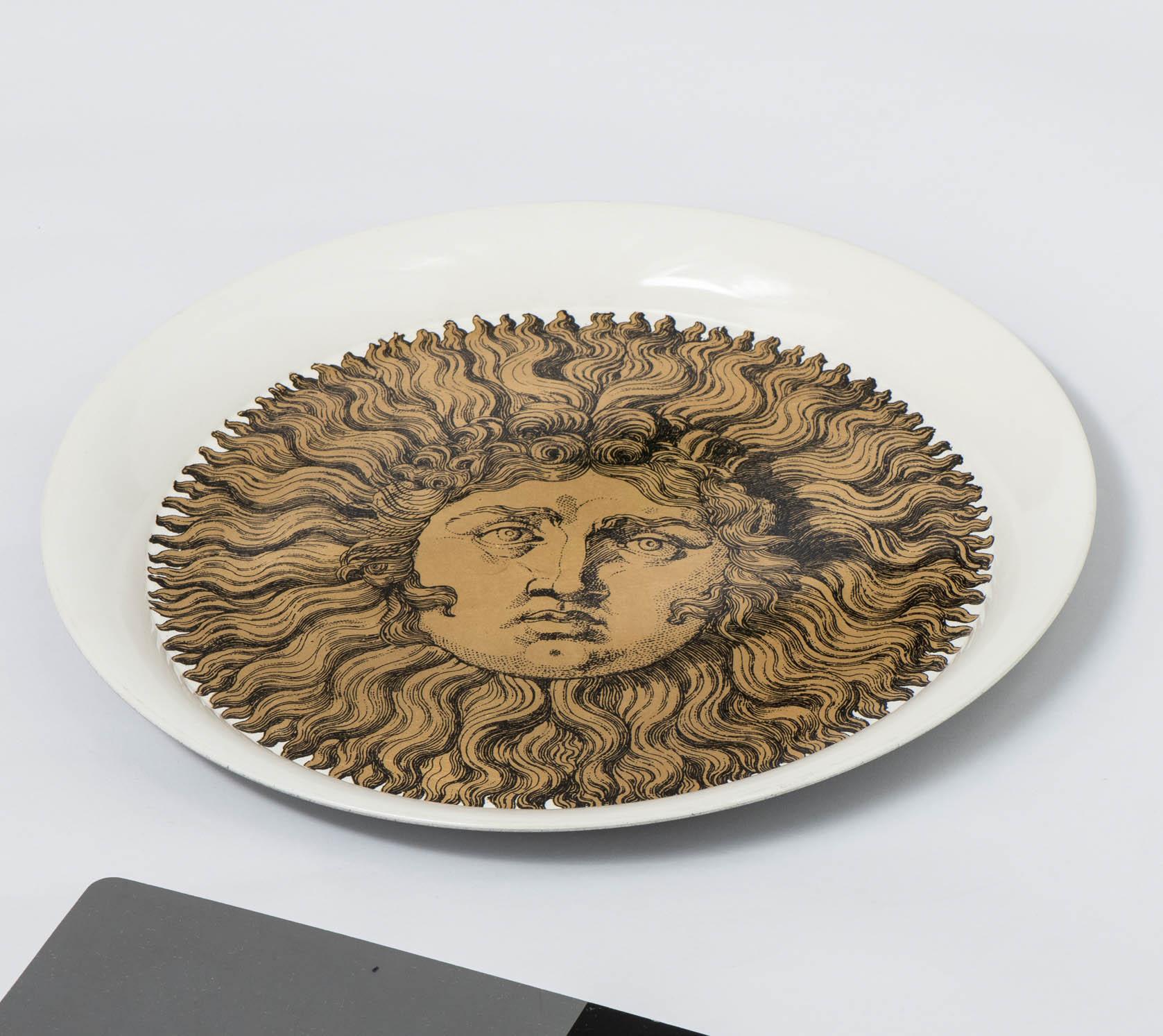 A Piero Fornasetti tray.
“Sole”.
Lithographically printed.
Hand colored and gilt highlighted on white ground.
Metal.
Italy,
circa 1960.
Measures: 39.5 cm diameter x 3 cm high.
 