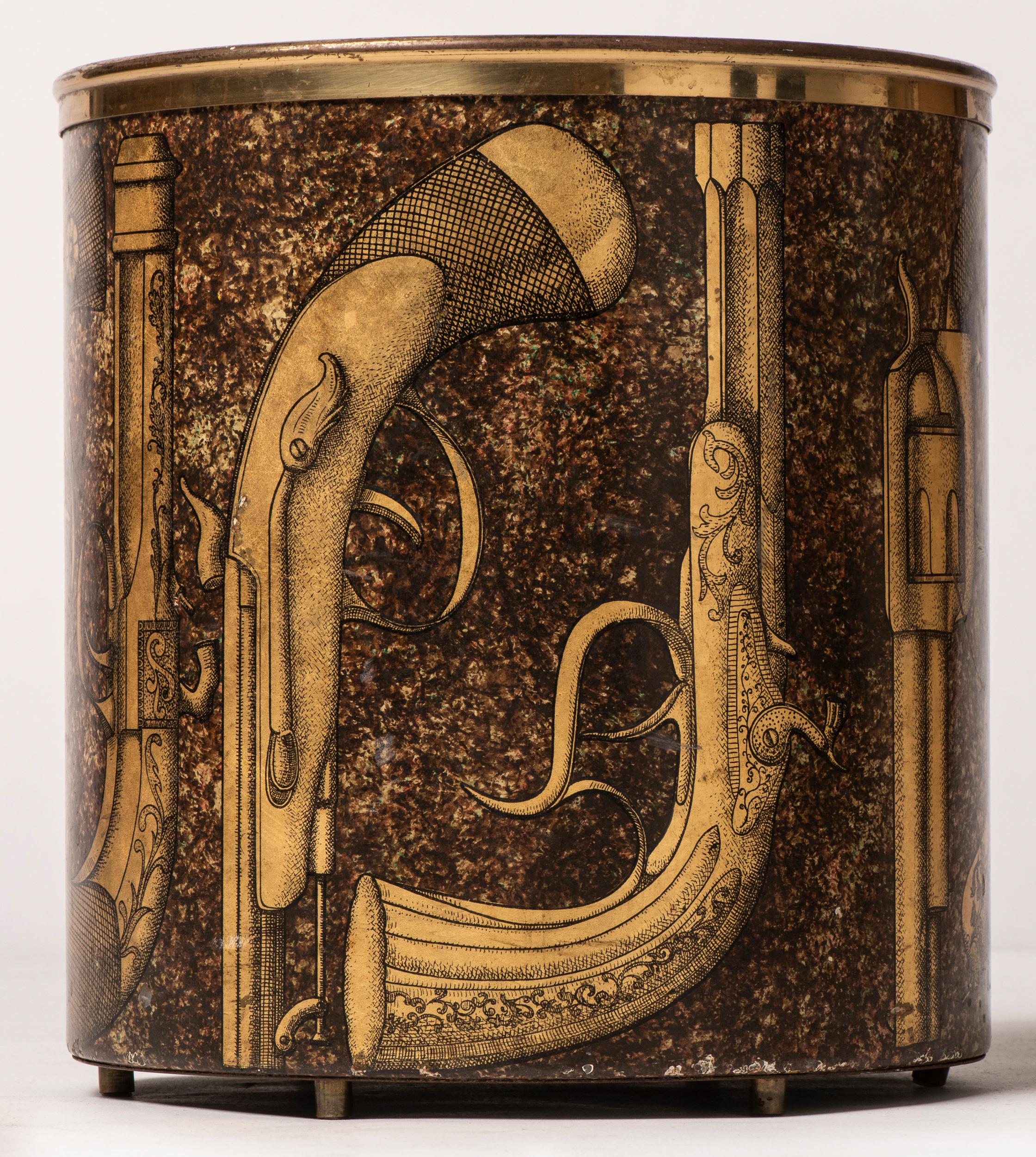 Piero Fornasetti waste paper bin.
“Pistole”
Metal lithographically printed and hand colored.
Mark to base.
Italy, circa 1960.
Measures: 28 cm height x 26 cm diameter.
 