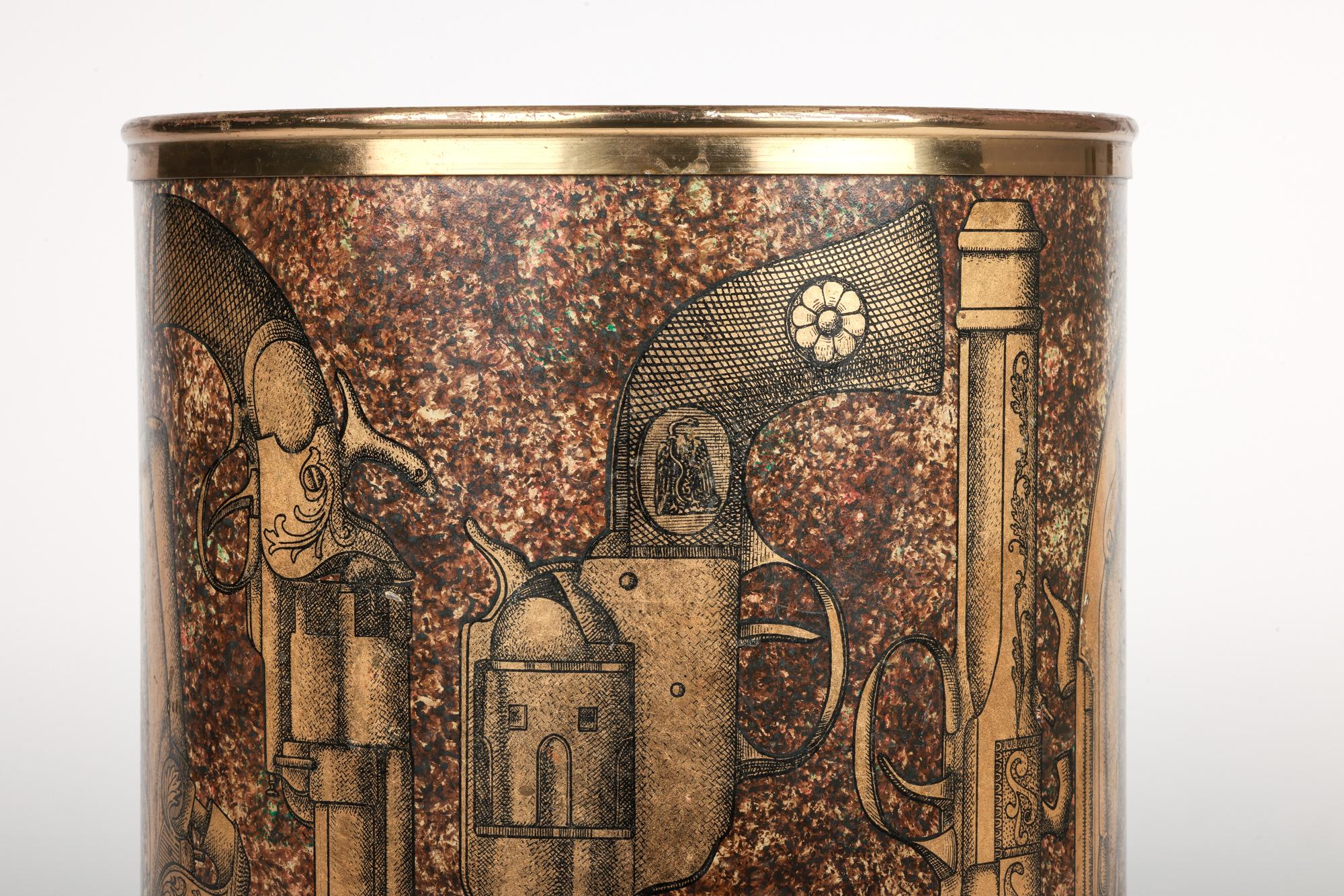A very stylish mid-century Italian metal refuse bin decorated with the ‘Pistole’ design by renowned Italian artist and designer Piero Fornasetti (Italian, 1913-1988) and dating from around 1960. The cylindrical shaped heavily made metal bodied bin
