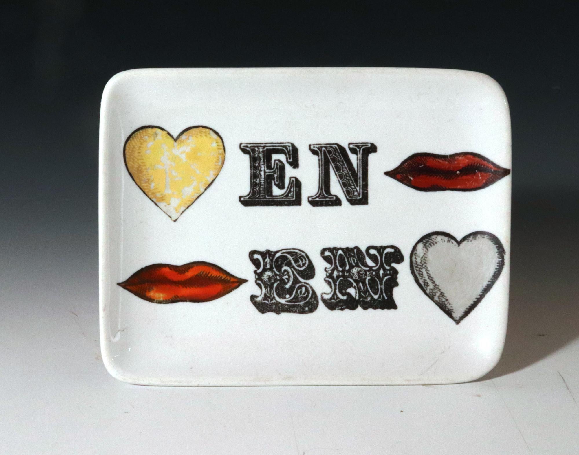 Piero Fornasetti Ceramic Pin Tray or Ashtray,
1950s-60s,

This rectangular ceramic tray features raised sides and a playful design by Piero Fornasetti. Two contrasting hearts, one yellow and one gray, are positioned in diagonally opposite corners.