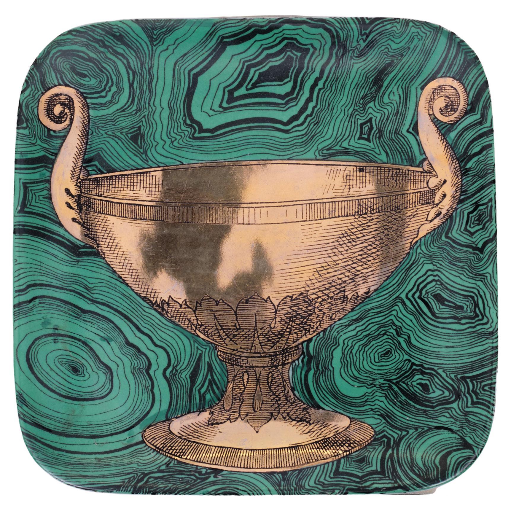 A ceramic decorative plate with an green faux malachite ground and painted in gold by Piero Fornasetti, Italy, manufactured in midcentury in 1950s.
This hand-colored decorative plate is one in a series of ‘faux malachite’ designs that Piero
