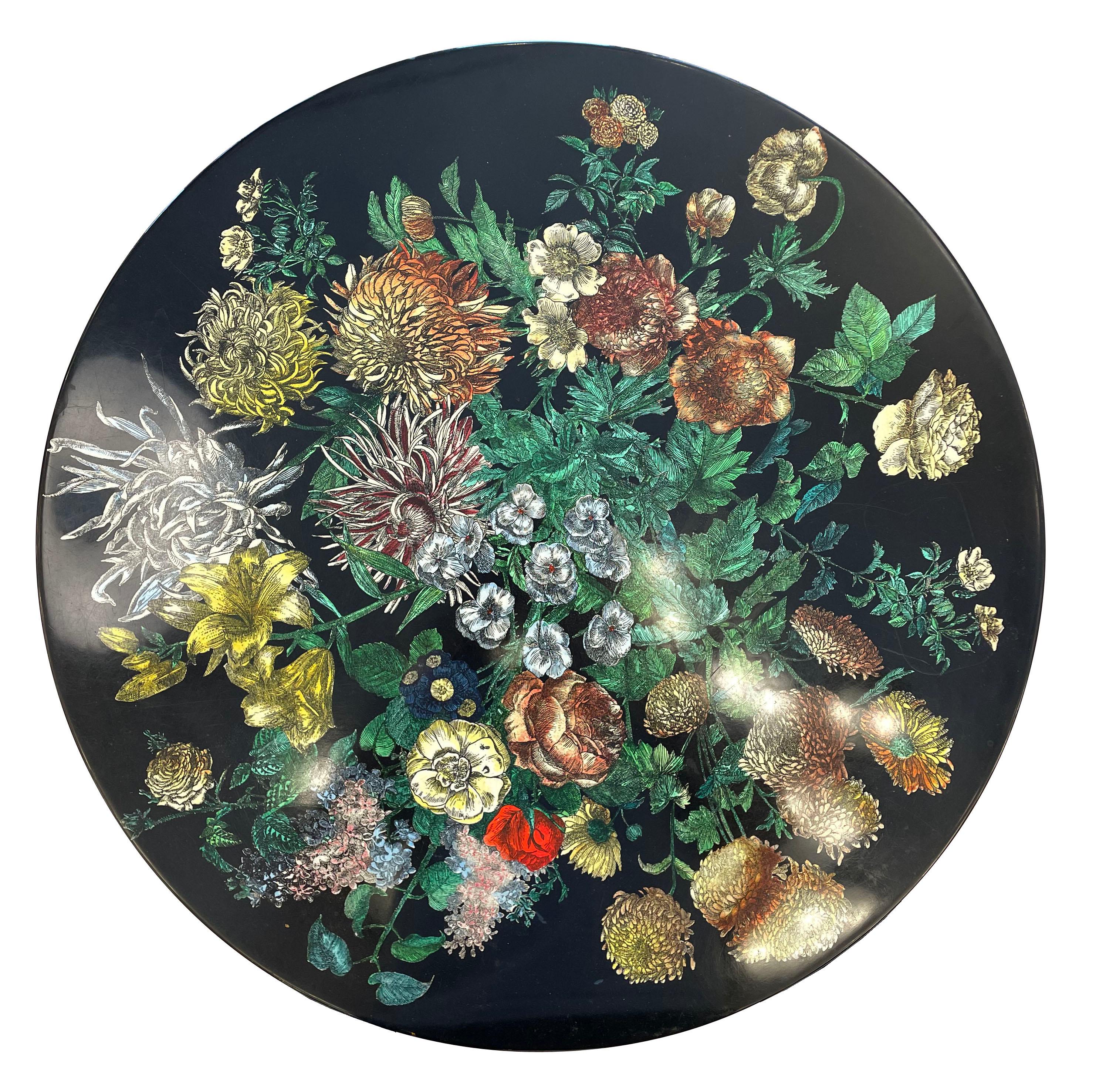 Large Piero Fornasetti side table with a colorful flower motif on a black background. Made of wood with four decorative legs and framing.

Condition: 
Excellent vintage condition, minor wear consistent with age and use

Measures: Diameter: