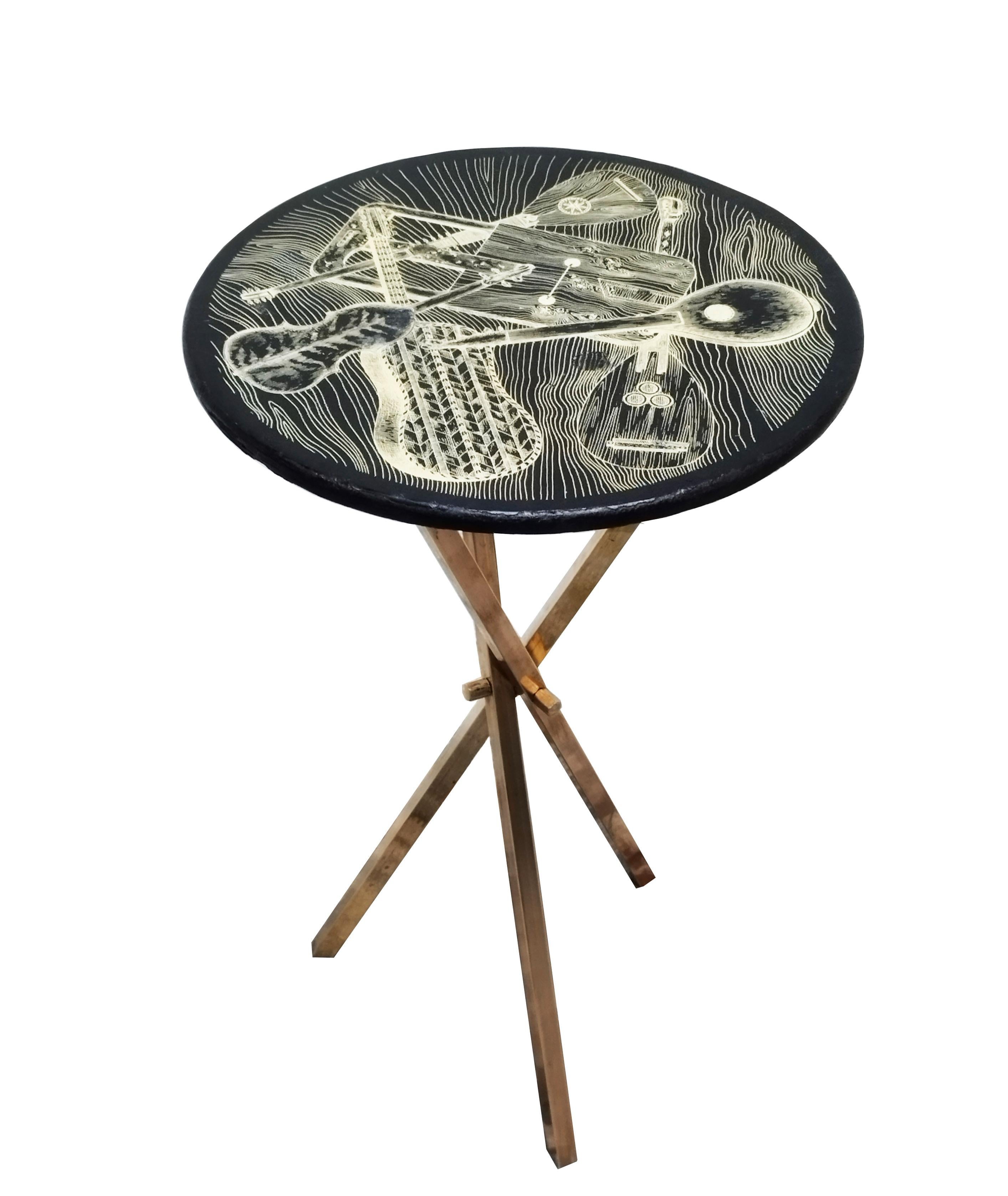 Brass tripod coffee table, under its original Fornasetti Milano Italia 1960 label. The coffee table is made of black and gold lacquered wood with a musical motif. This intriguing coffee table by Piero Fornasetti would work well as a side table on