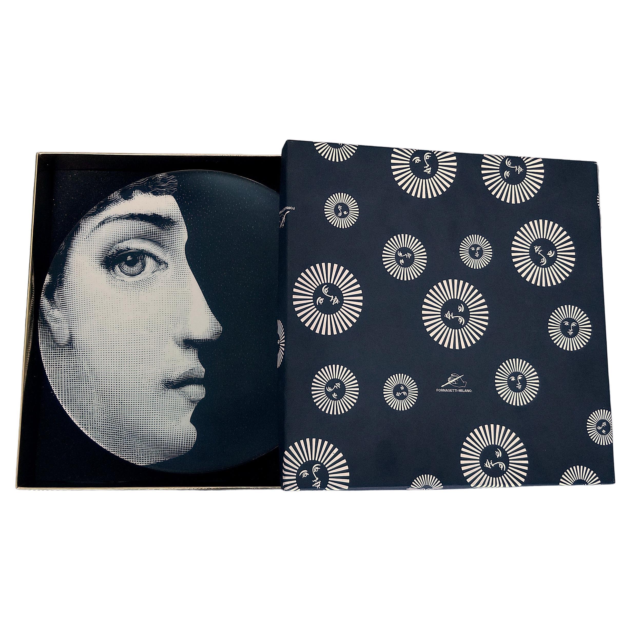 Il volto della cantante lirica Lina Cavalieri, musa di Piero Fornasetti, impreziosisce questo piatto decorativo da parete in porcellana. Questa è la variante numero 294 dell'iconica serie. Questa variante sorprendente e drammatica presenta una