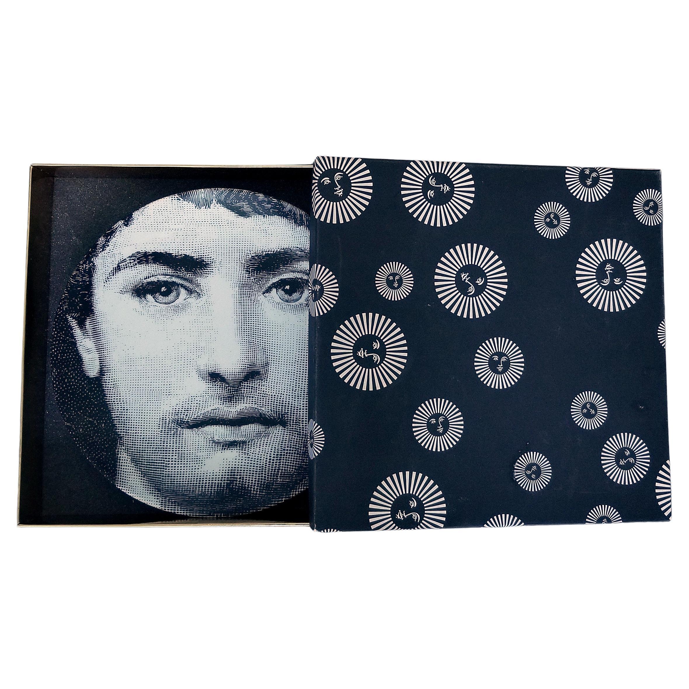 Il volto della cantante lirica Lina Cavalieri, musa di Piero Fornasetti, impreziosisce questo piatto decorativo da parete in porcellana. Questa è la variante numero 294 dell'iconica serie, che reinterpreta la musa come uomo o transgender. Questo