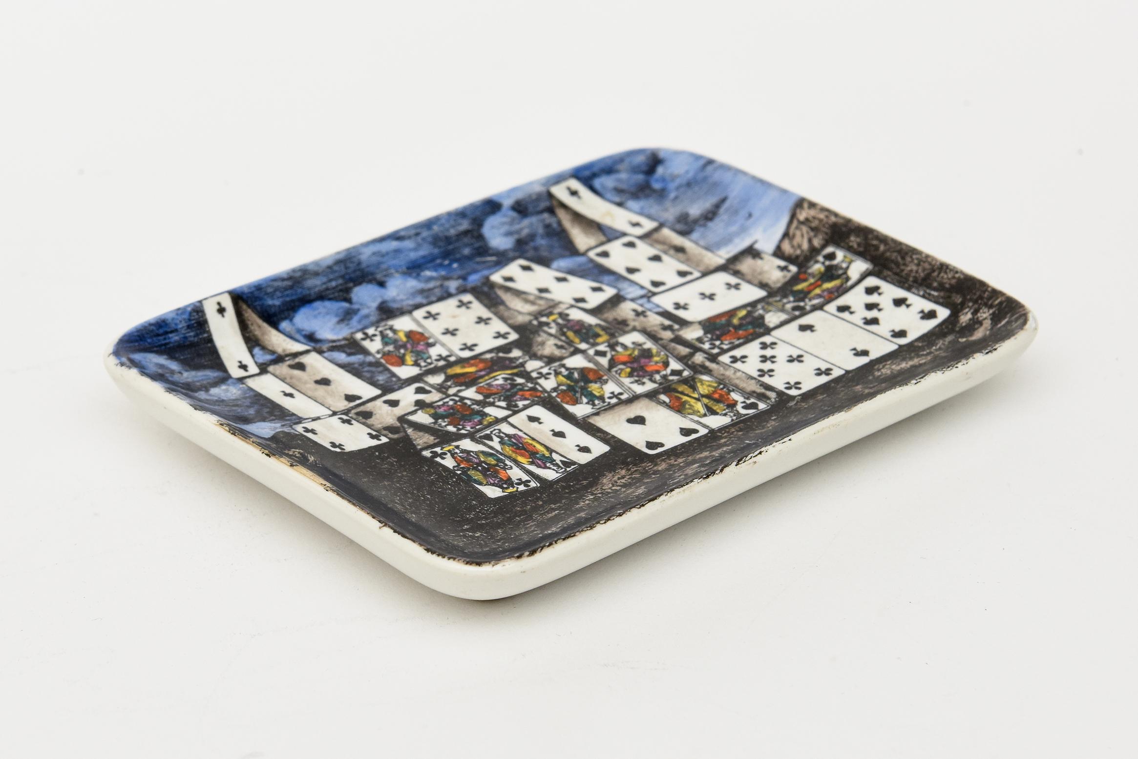 This dream like hallmarked Mid-Century Modern original Piero Fornasetti small tray, dish or desk accessory is lithographically hand painted porcelain. It is called the House of Cards and is set against a landscape in a surrealist style.I t is as if