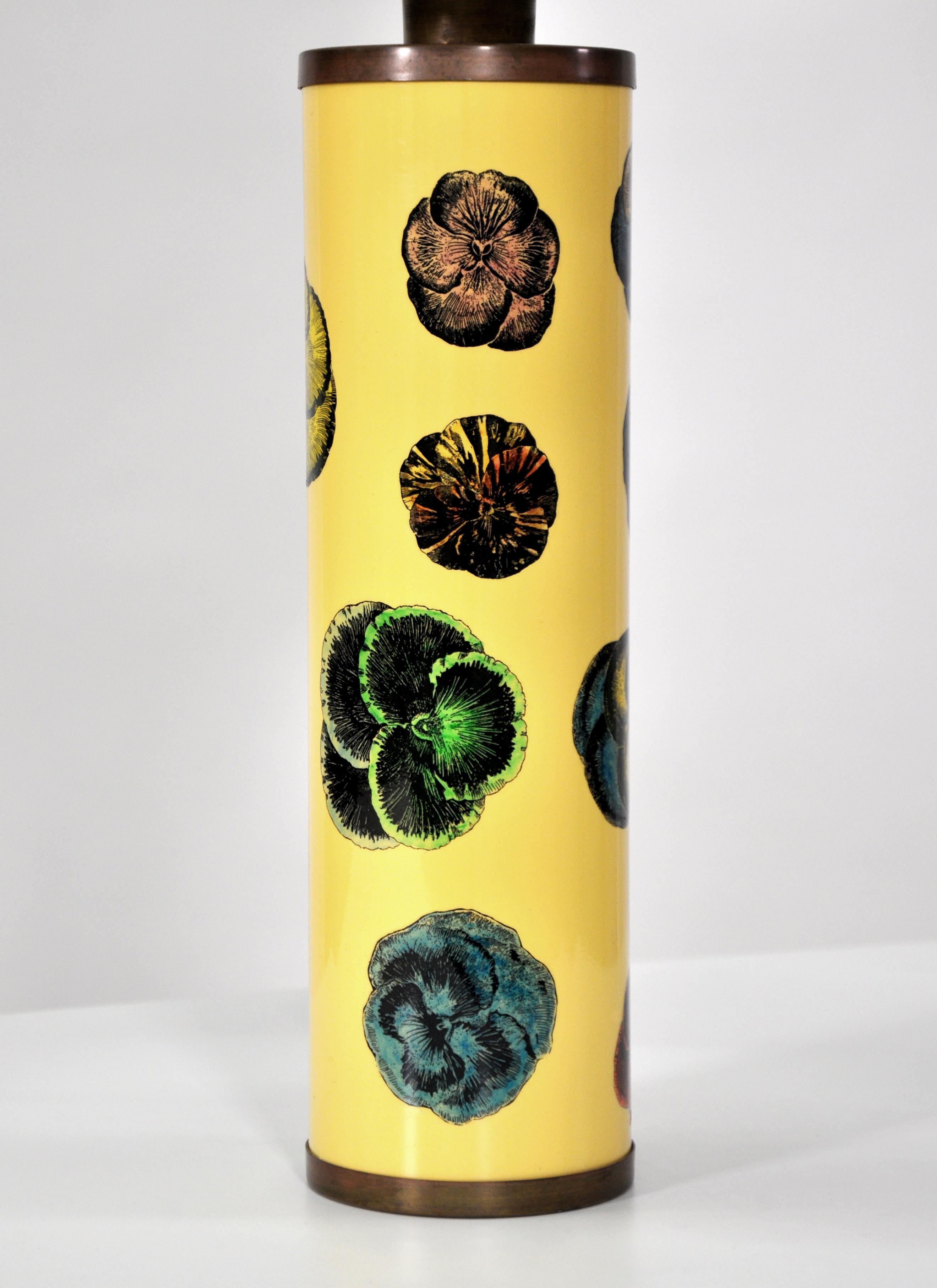 This vintage Mid-Century Modern lamp was designed in the late 1950s by the Italian master of playful and surreal self-expression, Piero Fornasetti. The brass lamp features lithographically printed green, blue, pink and purple violet flowers on a