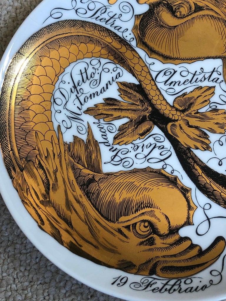 Este raro y codiciado plato de cerámica del zodiaco de Piero Fornasetti de época, decorado litográficamente y pintado a mano, tiene un fondo blanco con palabras escritas en negro que expresan el carácter y la personalidad del signo astrológico