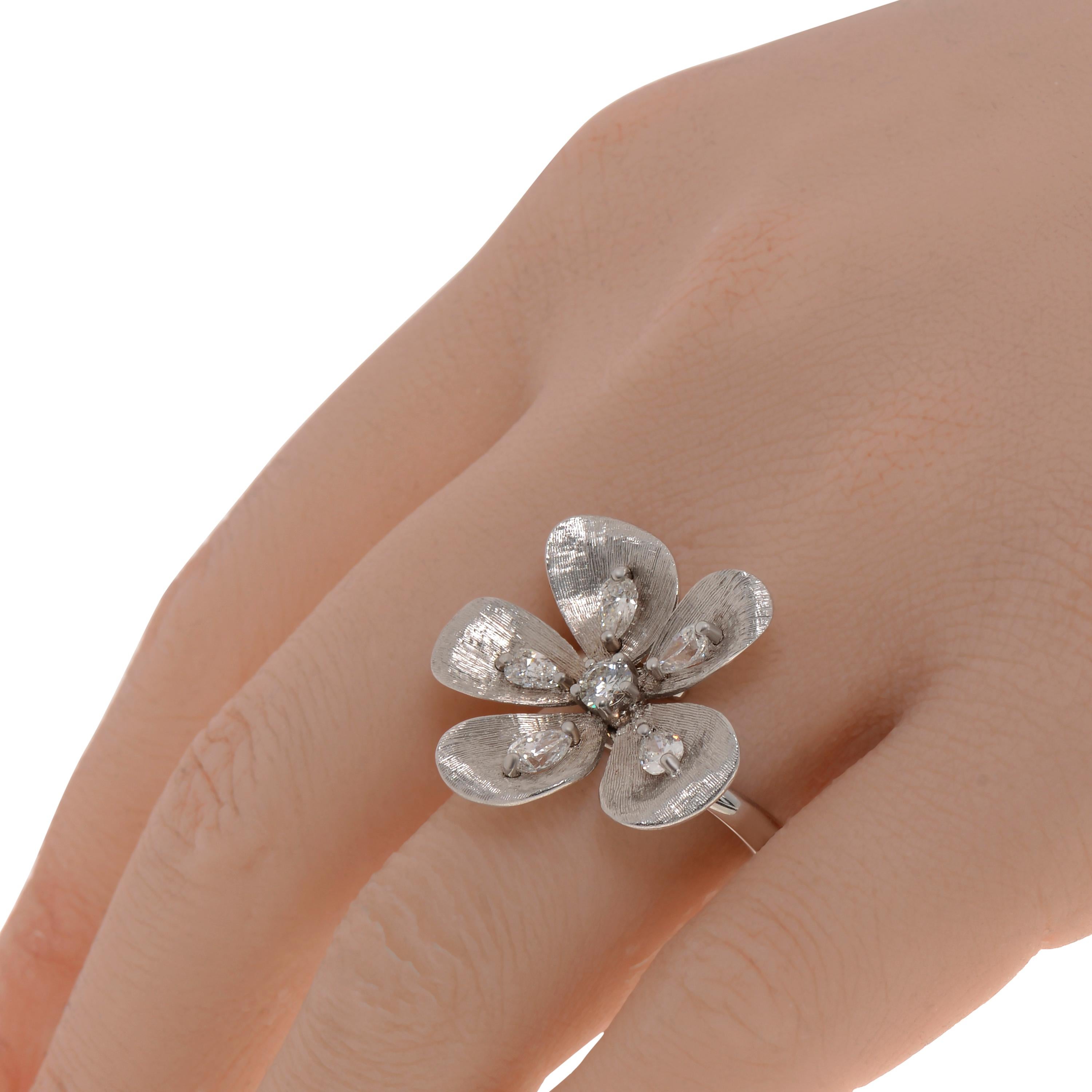 This bold Piero Milano 18K White Gold Cocktail Ring features a brilliant, center diamond surrounded by brushed gold petals with a teardrop diamond 0.92ct twd in the center of each petal on a polished white gold band. The ring size is 6.5. The