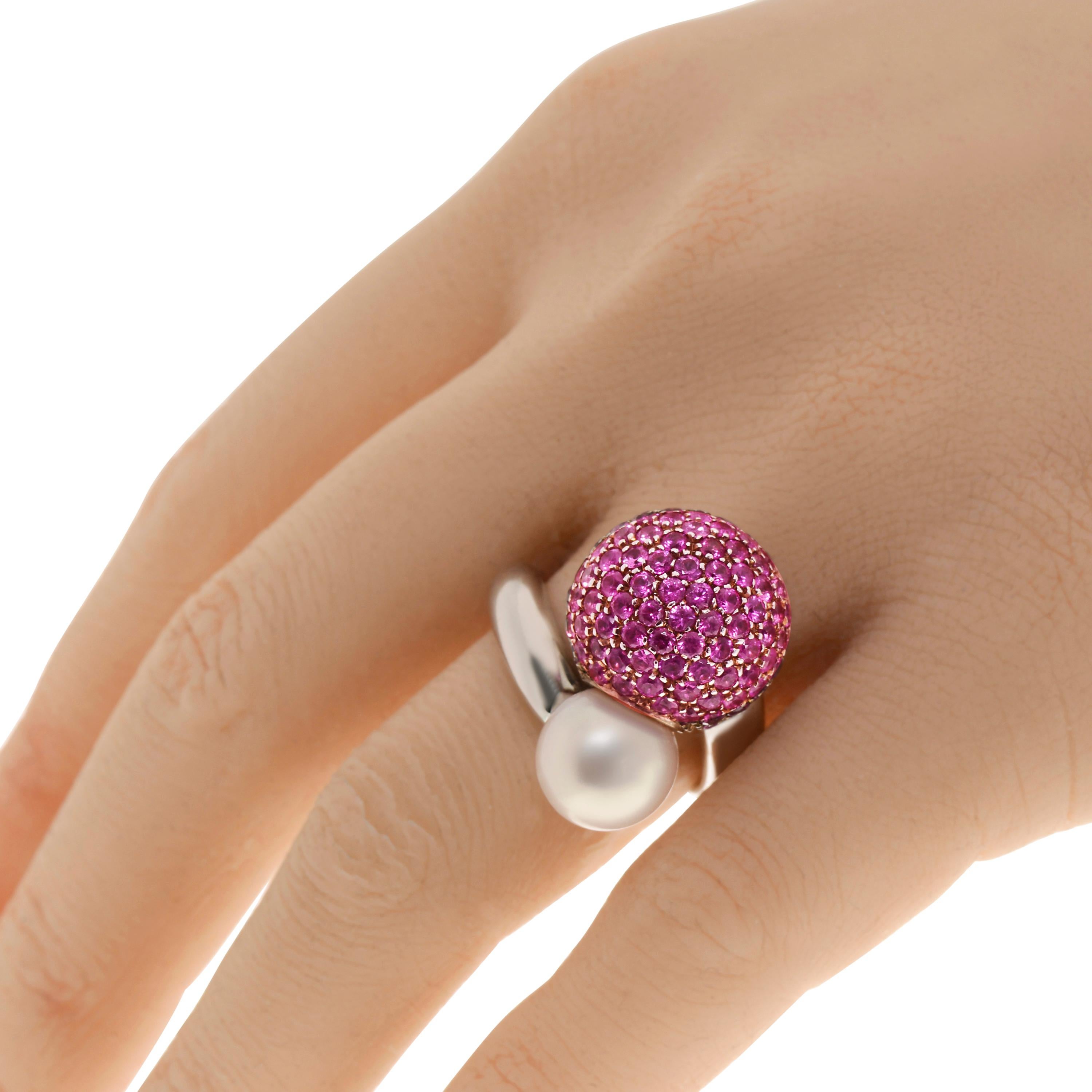This bejeweled Piero Milano 18K White Gold Cocktail Ring features a shimmering sphere of pink sapphire pave 4.64ct tw with a luminous1.5g pearl at each end of a polished white gold ring that wraps around your finger. The ring size is 8. The