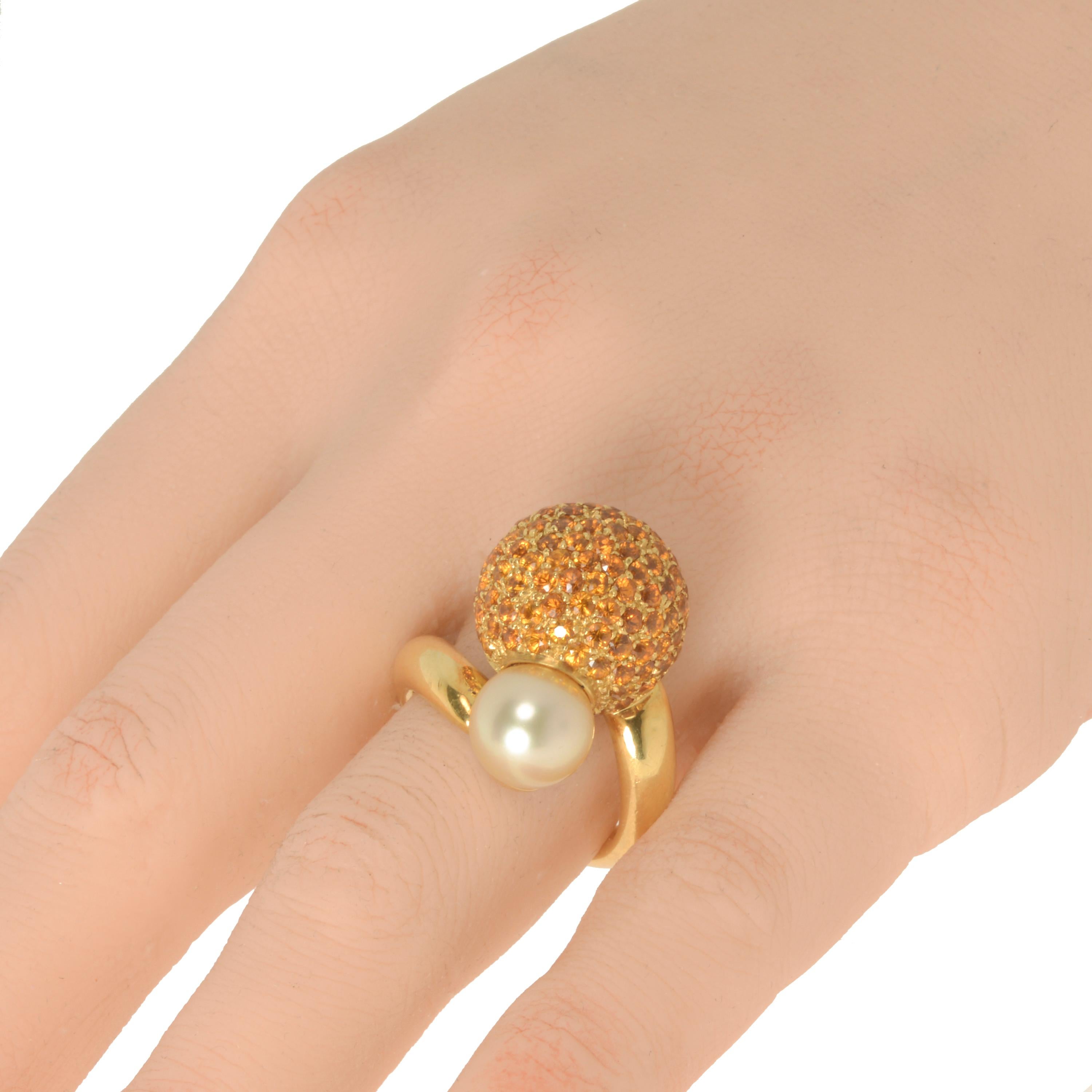 This striking Piero Milano 18K Yellow Gold Cocktail Ring features a shimmering sphere of yellow sapphire pave 5.02ct tw with a luminous 1.2g pearl at each end of a polished white gold ring that wraps around your finger. The ring size is 8.25. The