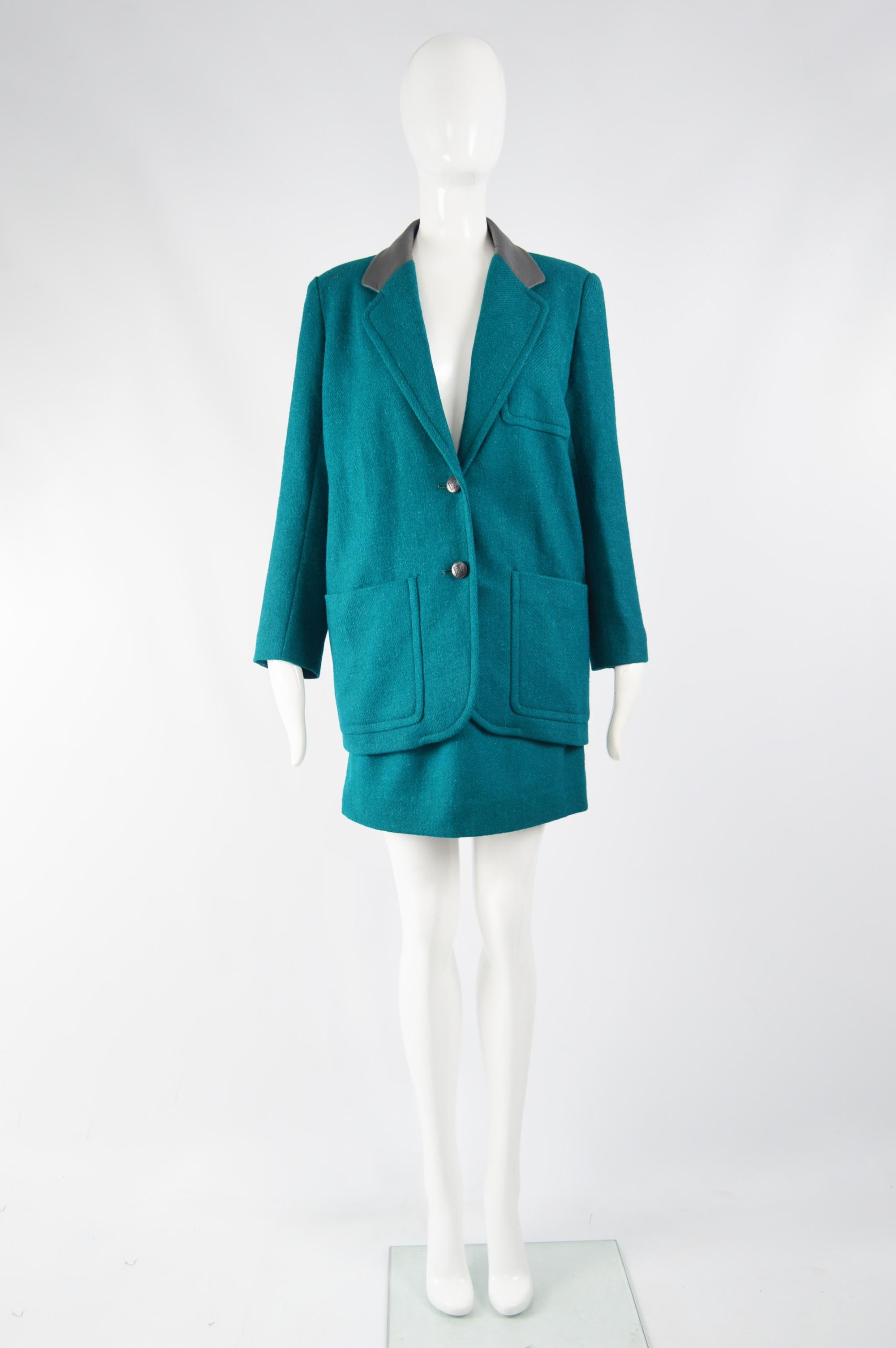 A fabulous vintage womens Pierre Balmain 2 piece skirt suit from the 80s. In a turquoise / teal wool with a dark grey leather collar. It consists of an oversized blazer with shoulder pads and a mini skirt (looks to have been shortened which gives a