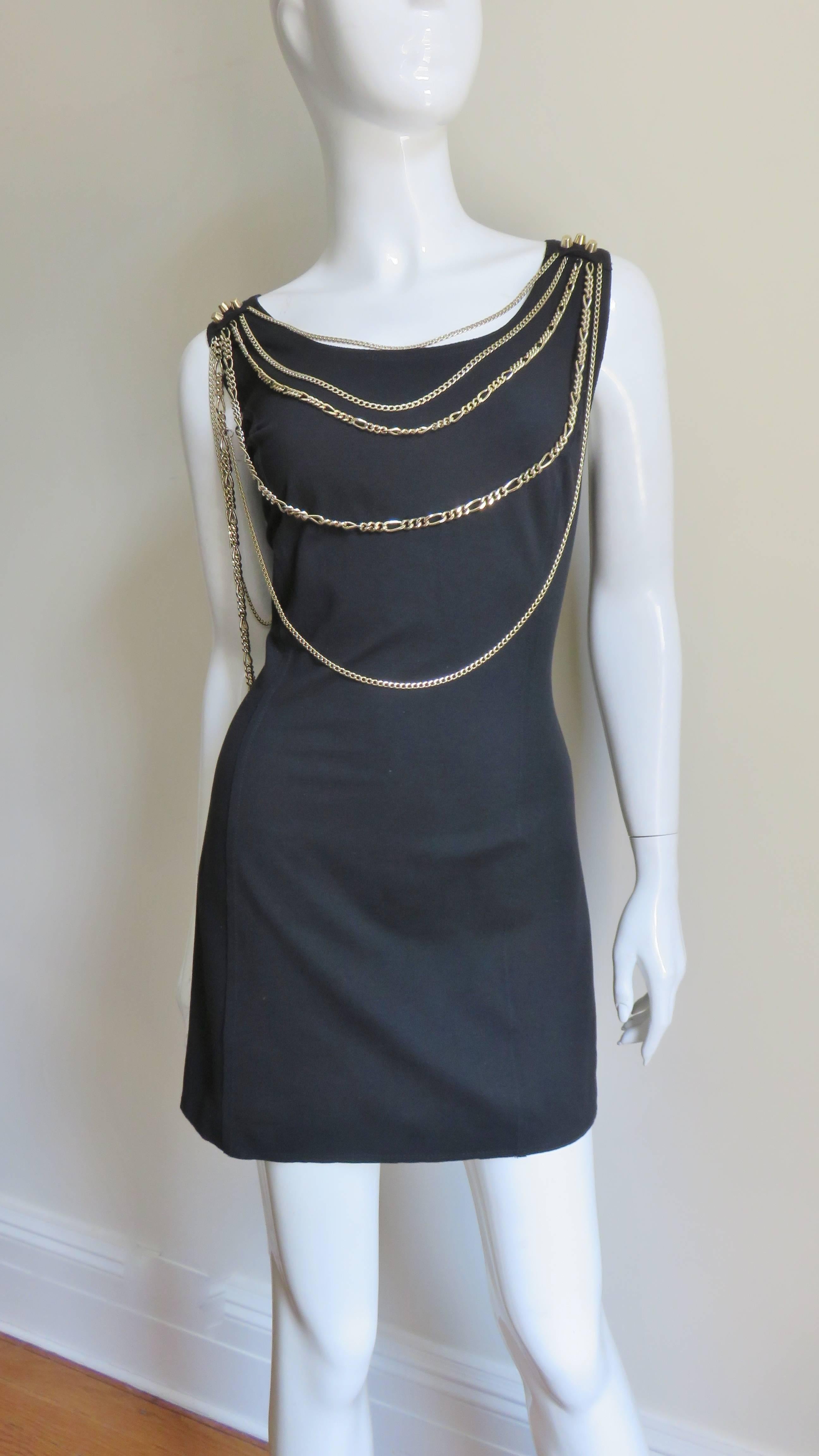 A fabulous black jersey dress from Pierre Balmain.  It is sleeveless with a soup neckline adorned with draping rows of gold chains of varying sizes and lengths all emanating from 3 gold metal posts on each shoulder.  The dress has princess seaming
