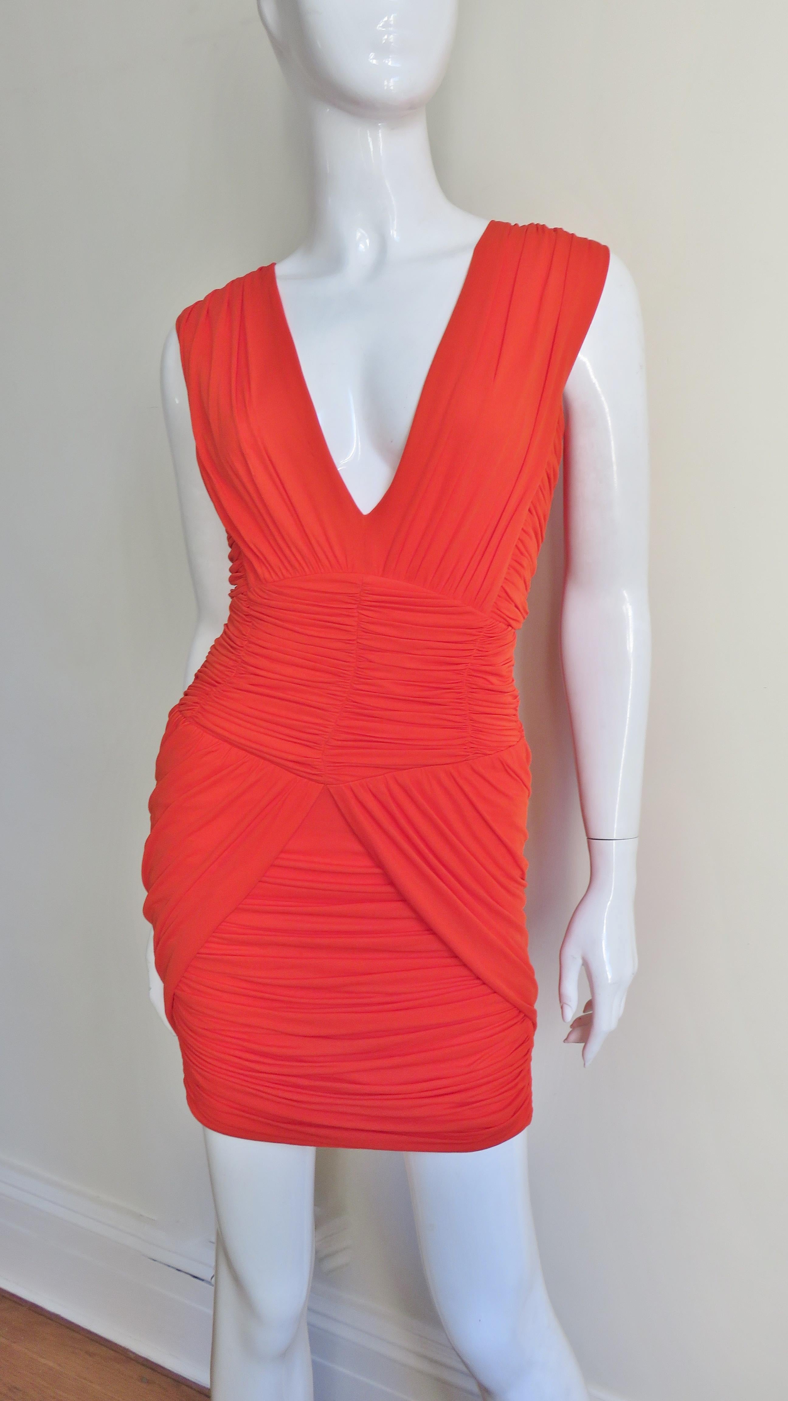 A gorgeous orange fine stretch silk dress from Pierre Balmain.  It  has a plunging V neckline with a vertically ruched bodice, horizontally ruched waist and skirt which is framed on either side with angular ruched panels.  It has a Balmain inscribed