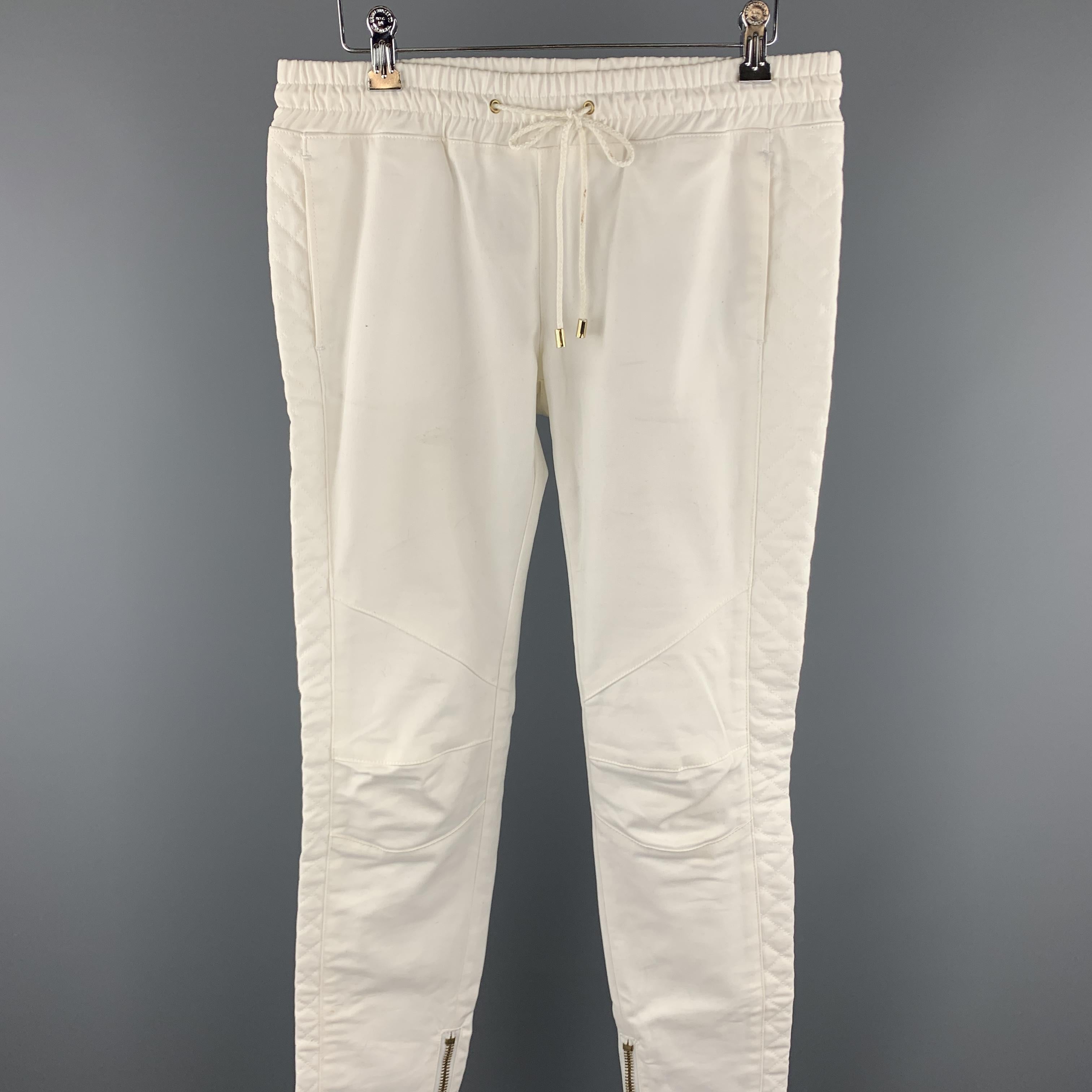 PIERRE BALMAIN causal pants comes in a cream cotton featuring a elastic waistband, side quilted panels, knee stitching, slit pockets, leg zippers, and a drawstring closure. Discoloration throughout. Made in Italy.

Fair Pre-Owned Condition.
Marked: