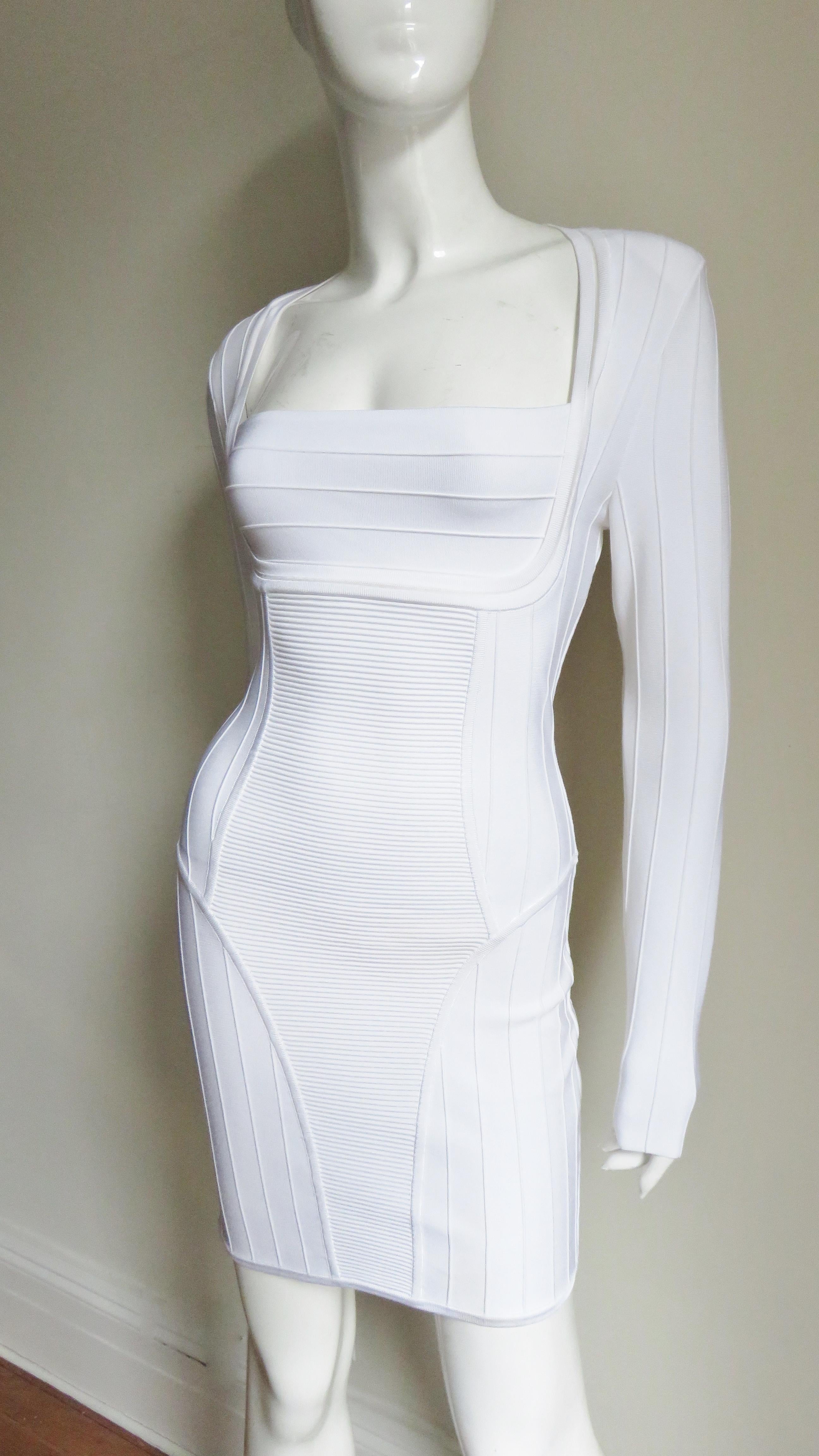 A fabulous white body conscious bandage dress from Pierre Balmain.   It has long sleeves, a square cut neckline, and fabulous ribbed panels accentuating the waist and bust. It is unlined with a gold Balmain inscribed back zipper and small pads at