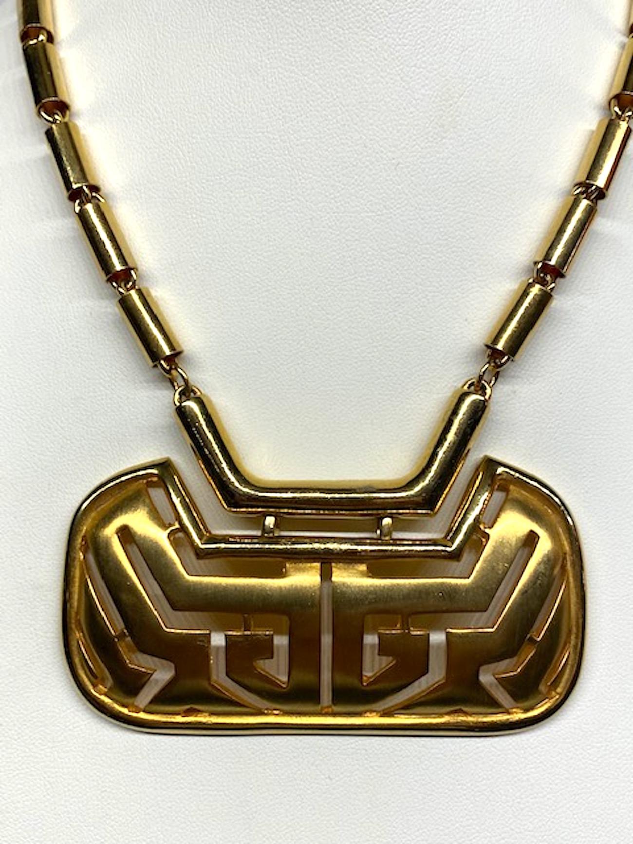 A chic late 1970s to mid 1980s shiny and satin gold abstract pendant necklace by Pierre Cardin. The right and left barrel link chains are 8 inches long. They meet in the middle at a solid 2.25 inch 