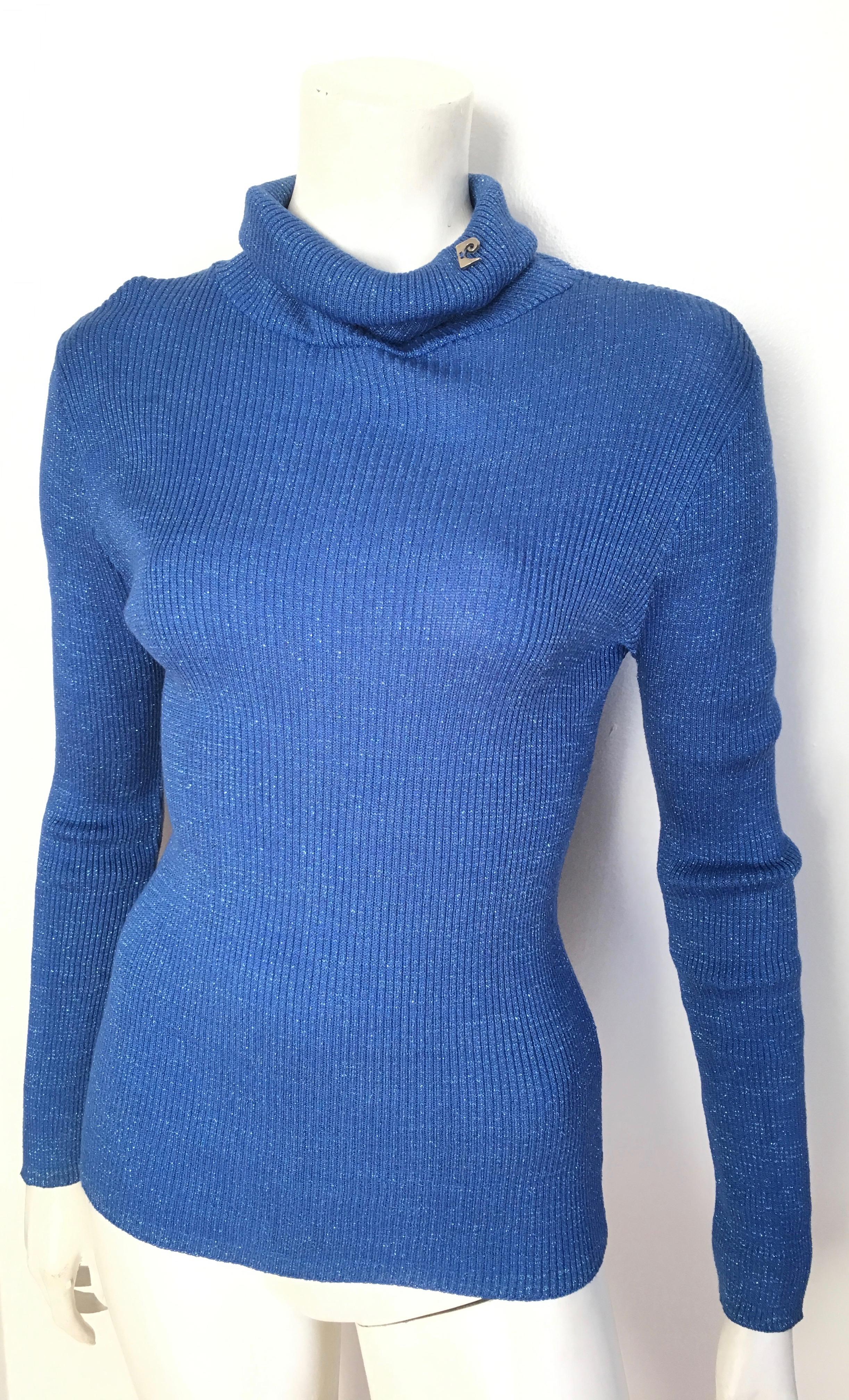 Pierre Cardin 1980s blue metallic knit turtle neck long sleeve pullover is a size 4 / 6. 
Iconic Pierre Cardin logo sewn on the collar.
This jazzy blue metallic knit pullover is an instant classic.  You can wear this pullover with your 1980s Calvin