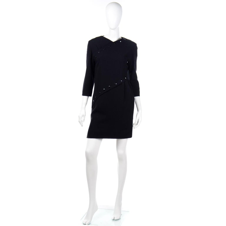 This is a vintage Pierre Cardin take on the little black dress! This black wool crepe shift dress has two rows of snaps crossing diagonally from the left shoulder and waist to the underarm and low hip. These snaps are decorative not functional, and
