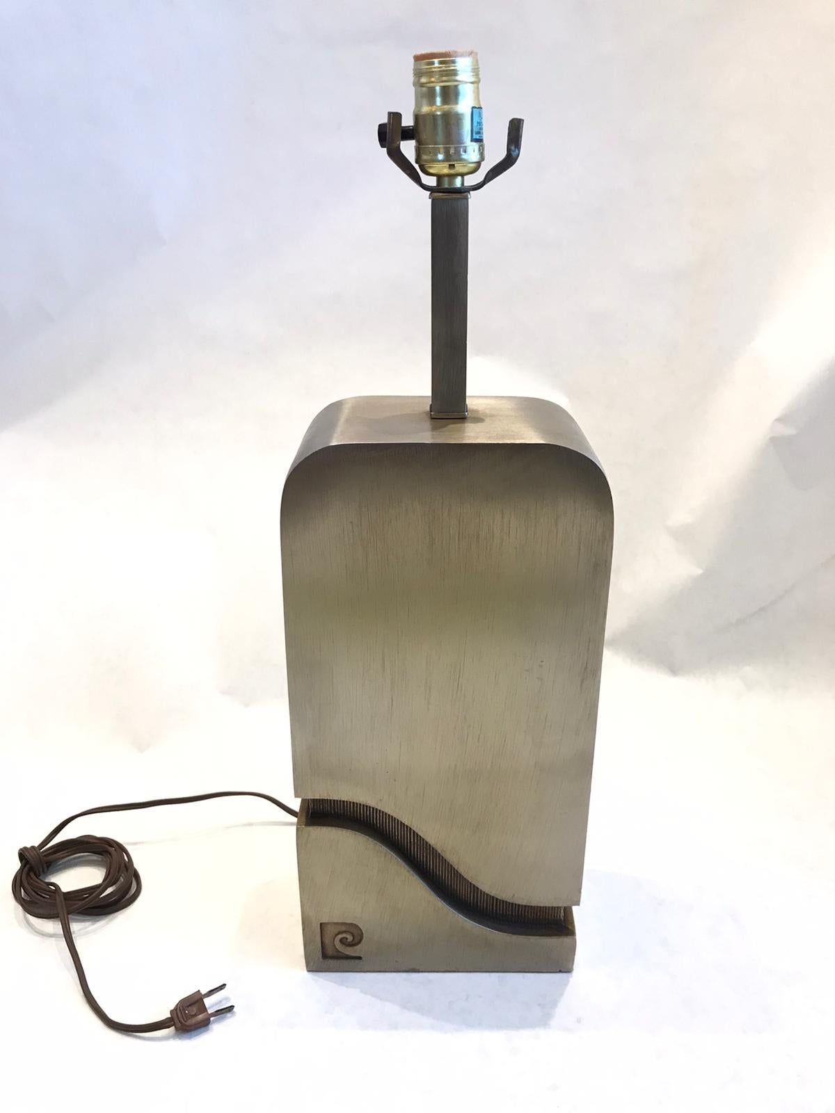 Modern bronze finish steel table lamp with heavy rectangular body, created by Pierre Cardin in the 1970s. The piece has the Pierre Cardin monogram on the front side and is in great vintage condition, with some age-appropriate patina and wear.