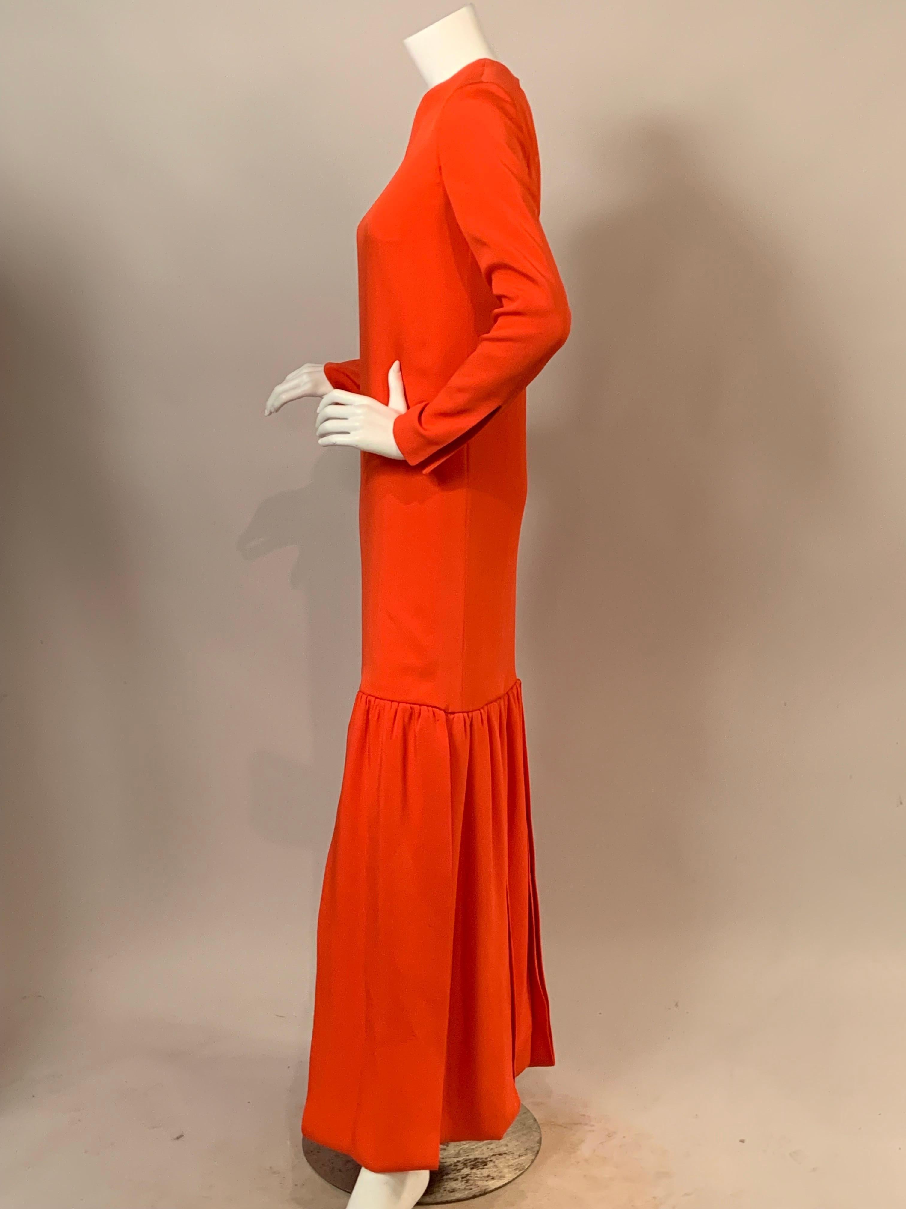 Se trata de un fabuloso vestido de los años 60 diseñado por Pierre Cardin en crepé de seda de color naranja brillante.  El vestido tiene escote redondo, mangas largas con una costura abierta en la muñeca, cintura caída y su famosa falda