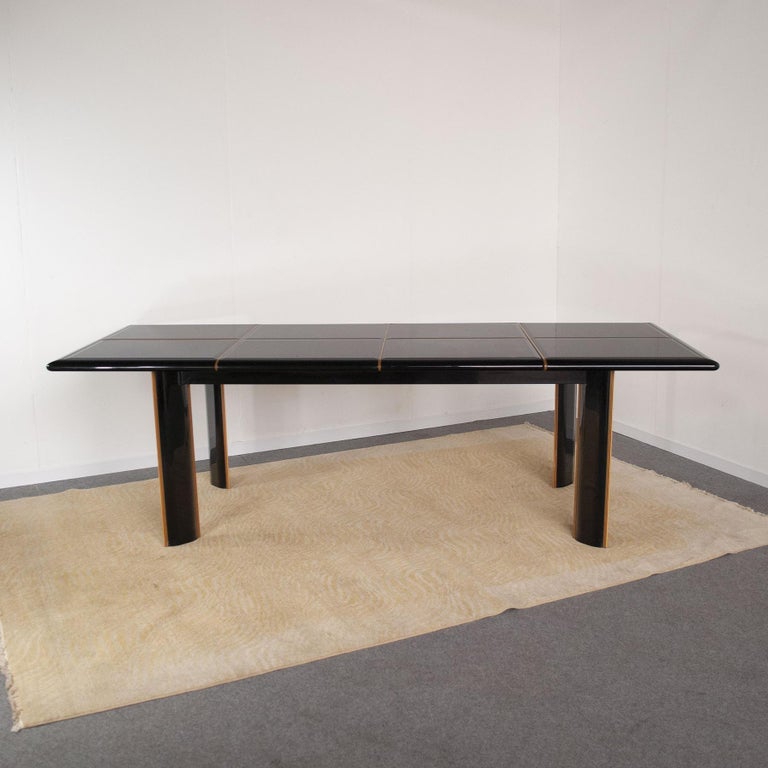 Large black lacquered extensible dining table with top composed of rectangular shaped lacquered glass elements, elegant inserts in light maple wood are present throughout the table, a model made in France by the designer Roche Bobois for Pierre