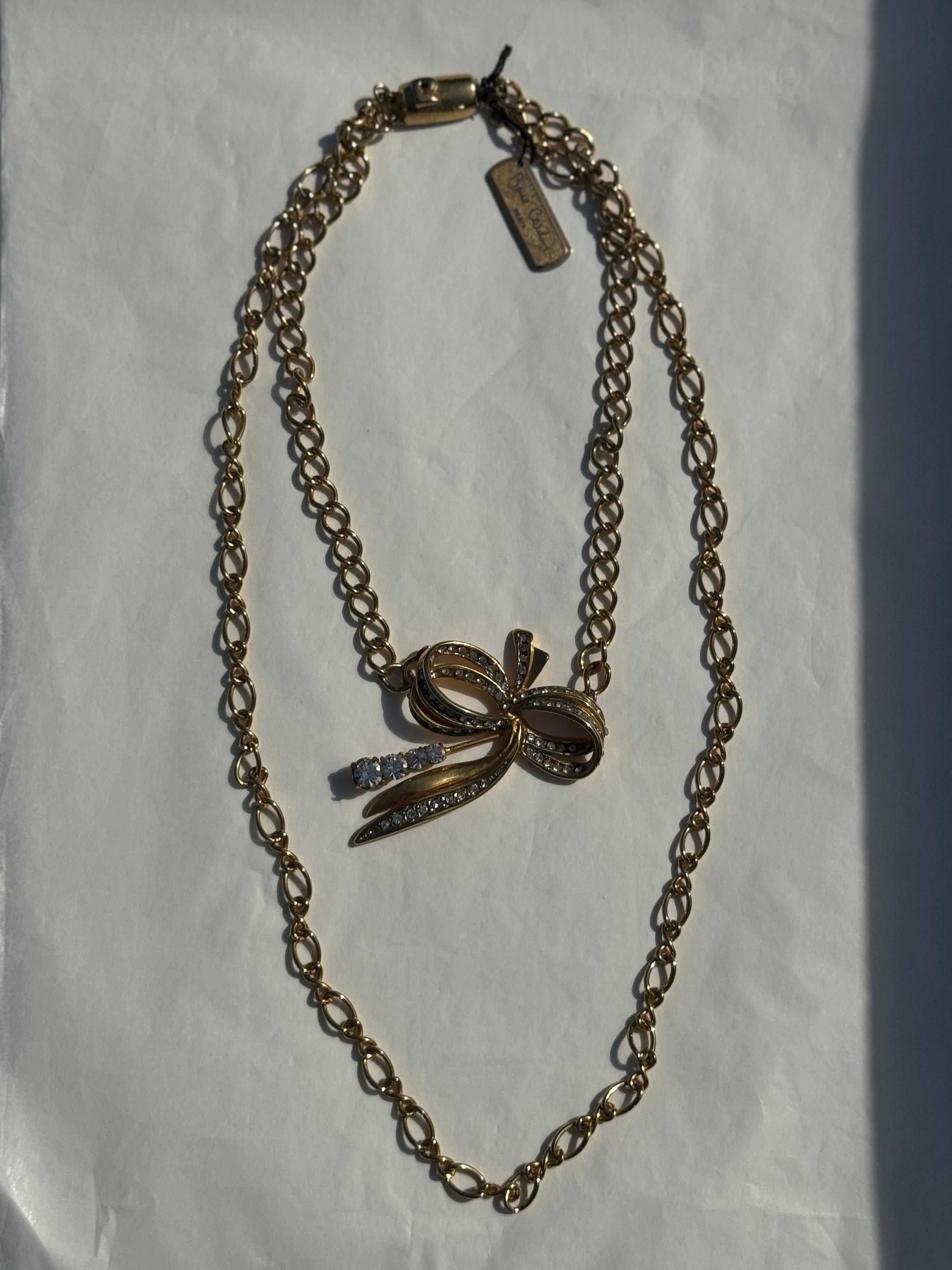 Adéntrese en la elegancia atemporal con este impresionante collar vintage de Pierre Cardin, una radiante expresión de sofisticación parisina y diseño icónico.

Esta pieza presenta una doble cadena dorada que le confiere un aspecto rico y