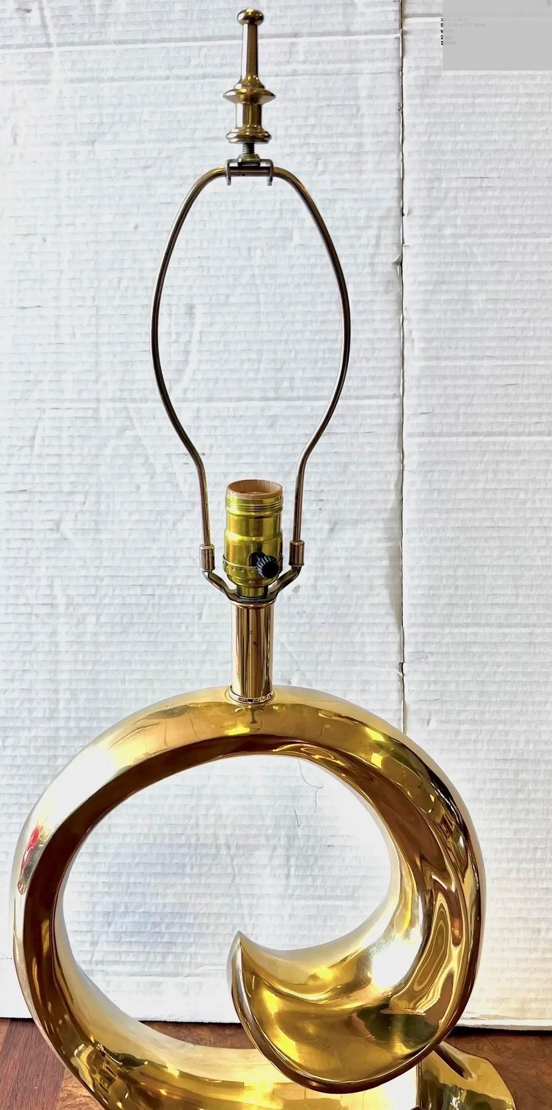 Iconic brass swoosh lamp features reflective brass design that captures the essence of modern elegance.  It stands 26