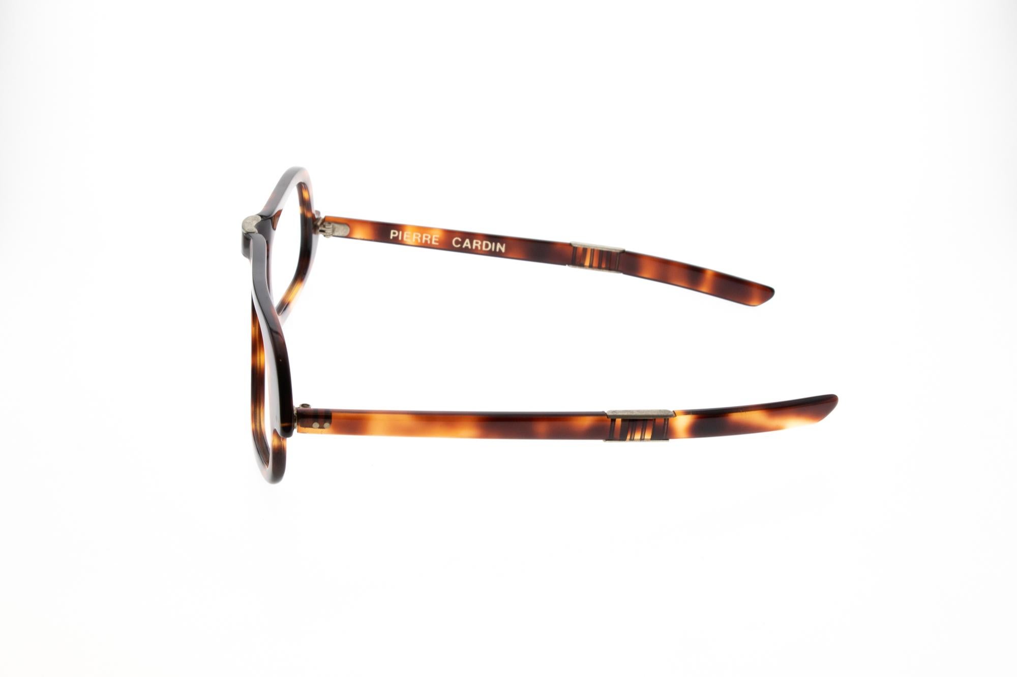 Ces lunettes pliables fabriquées par Pierre Cardin sont de couleur tortue et n'ont jamais été portées (deadstock). Pierre Cardin était un célèbre créateur de mode et a eu beaucoup d'influence dans le monde de la mode. Il a travaillé avec beaucoup de