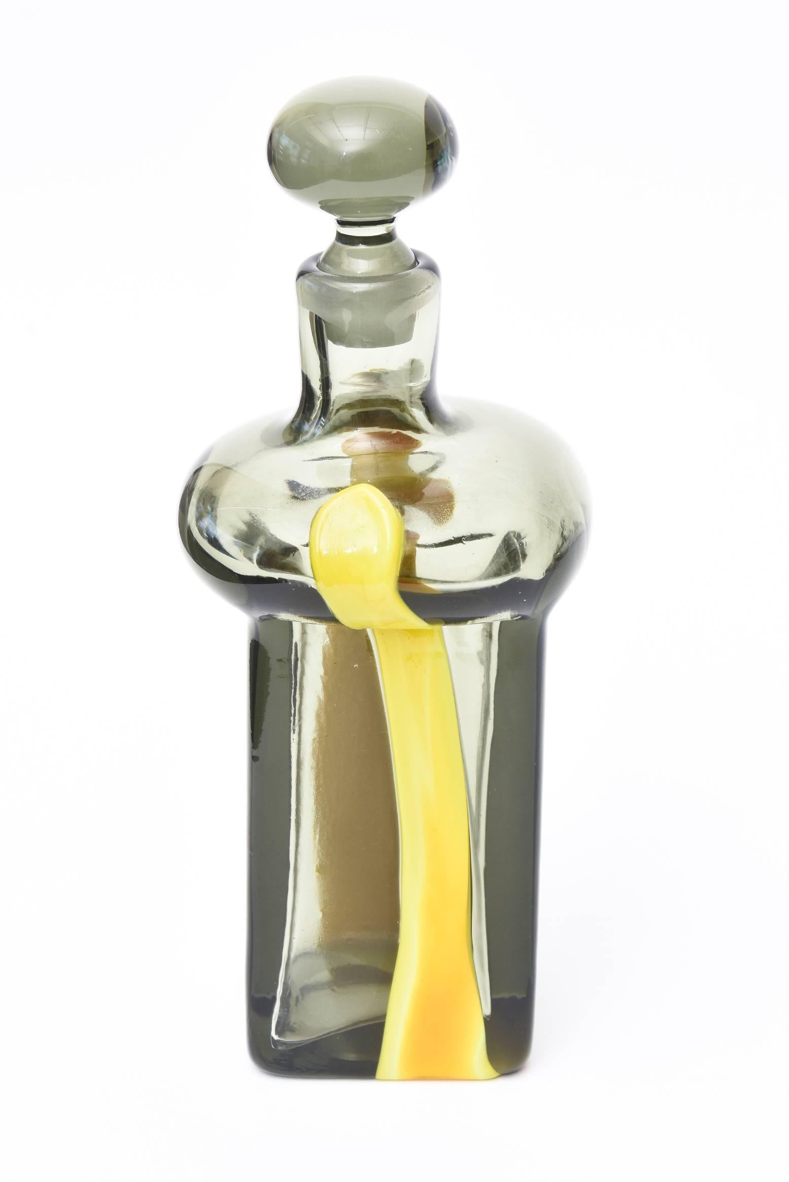 This tres chic Italian Murano sculptural decanter was designed by Pierre Cardin for Venini. The grey smoked glass is accented on the sides by blobs of thick linear yellow applied blown glass. It is a sculptural decanter bottle and a great barware