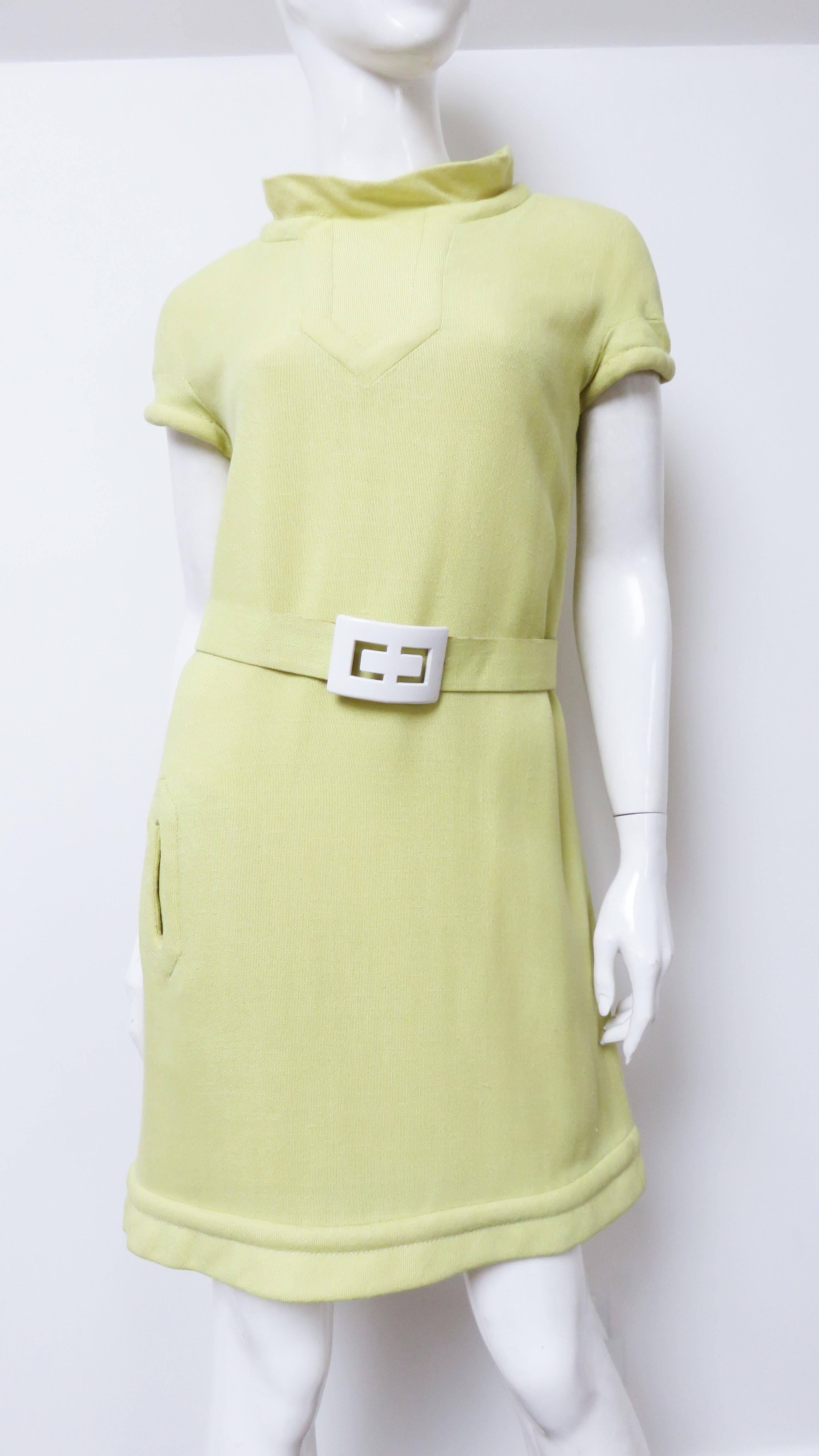 An iconic 1960s yellow linen dress from Pierre Cardin.  It has a stand up collar and cap sleeves with trapunto embroidery around them, the hem and front pocket. It has a handstitched matching back zipper, yellow lining and comes with a matching belt