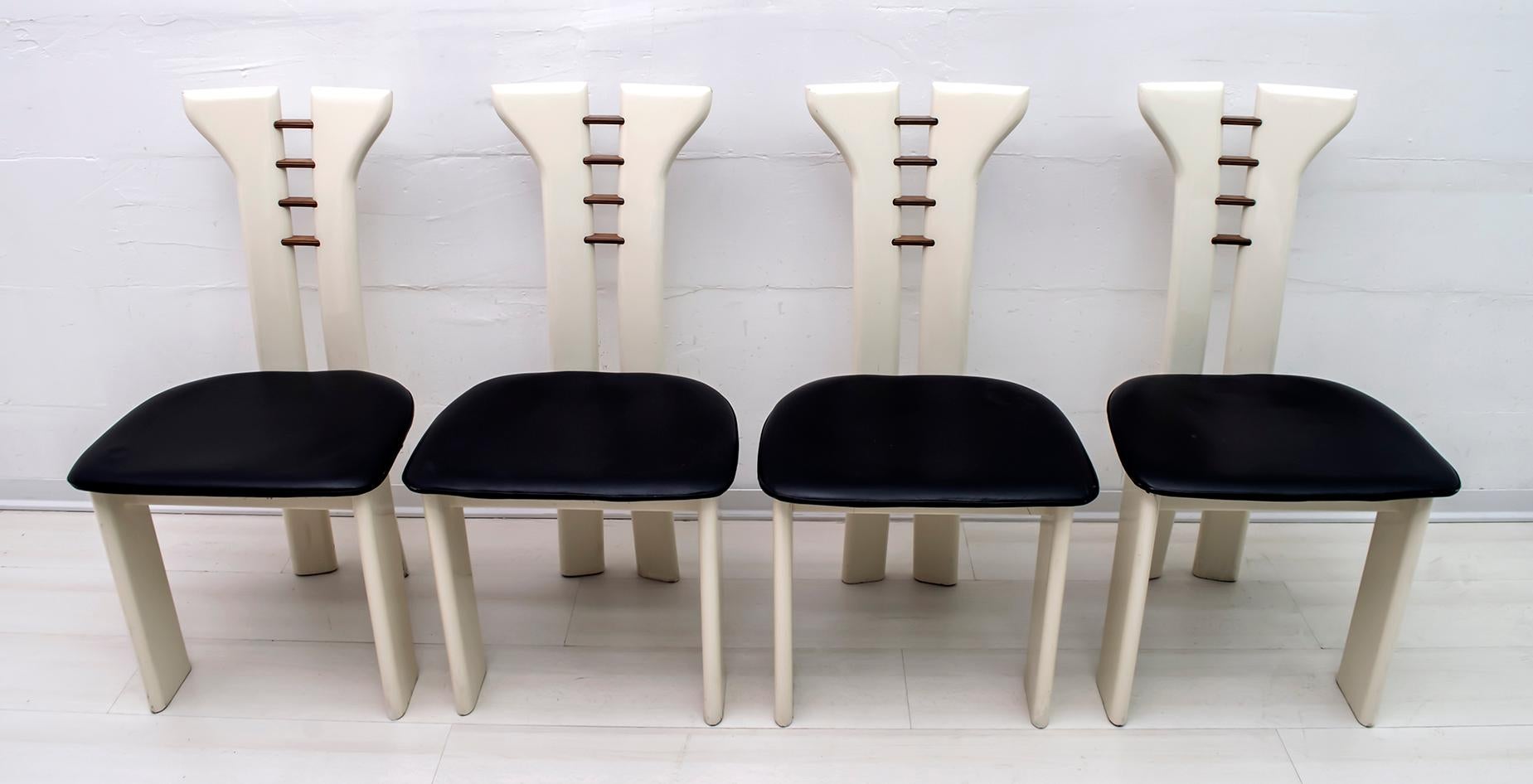 Beautiful set of 4 dining chairs by Pierre Cardin for Roche Bobois. Ivory lacquered solid wood chairs with black leather seats. Captivating wooden details layered on the back. Dark wood, probably rosewood or walnut, layered with maple. The attention