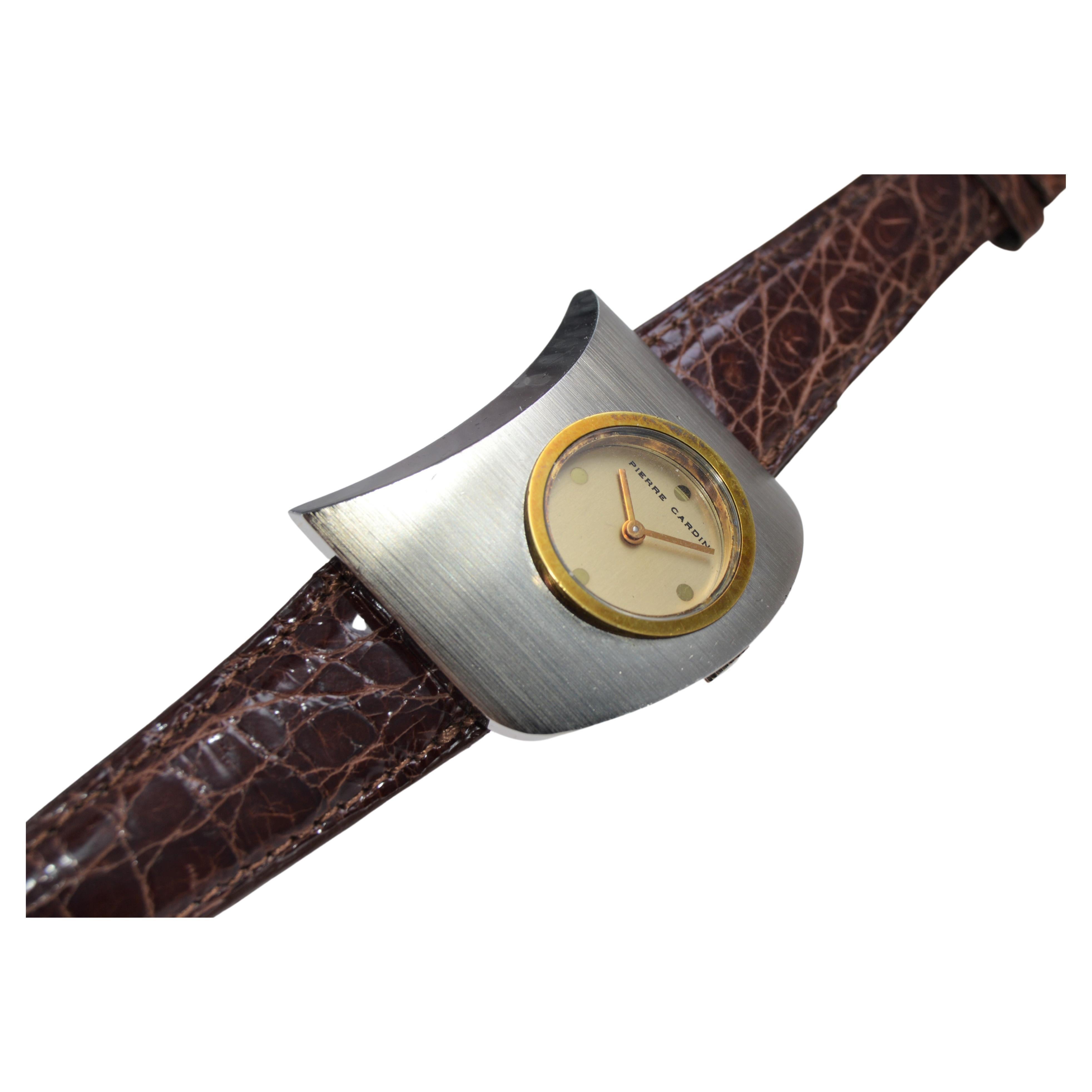 FACTORY / HOUSE : Pierre Cardin / Movement by Jaeger Le Coultre
STYLE / RÉFÉRENCE : Moderne 
MÉTAL / MATERIAL : Acier inoxydable / Lunette en or jaune massif
DIMENSIONS : Longueur 40mm  X Largeur 32mm
CIRCA : années 1970
MOUVEMENT / CALIBRE :