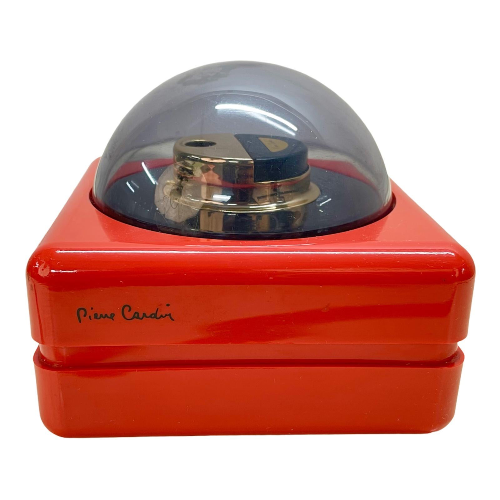 Incredible midcentury red table lighter with smoked plexiglass dome. This piece was designed and signed by Pierre Cardin and produced in France during the 1970s.

The article is endlessly fascinating for not having been used and being brand new.
