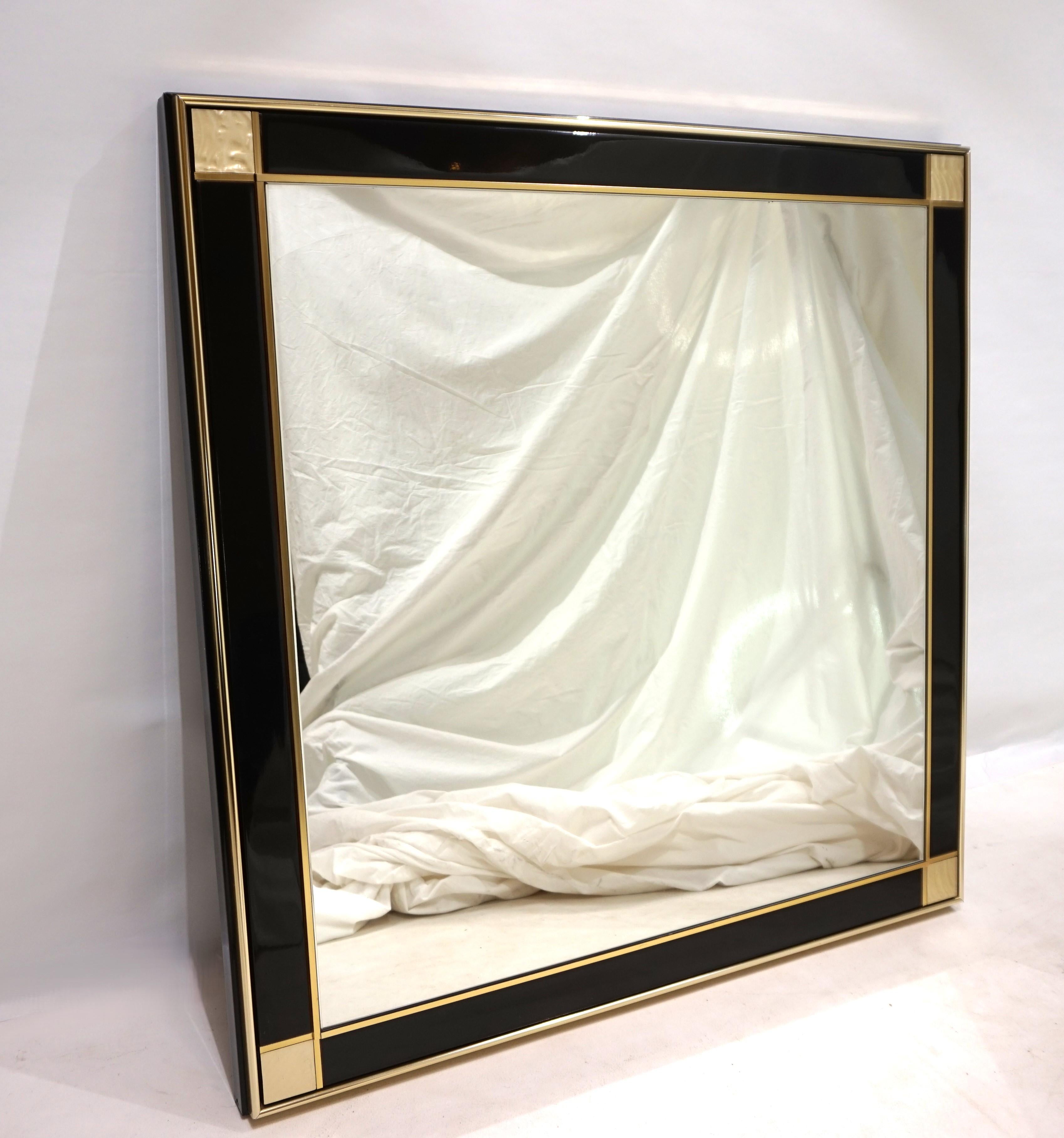 Dieser außergewöhnliche Wandspiegel von Pierre Cardin in schwarzem Klavierlack ist in sehr gutem Zustand. Der Spiegel besticht durch seine Messingstangen, die das makellose Glas einrahmen. Die Ecken des Spiegels sind mit goldenen, opalisierenden