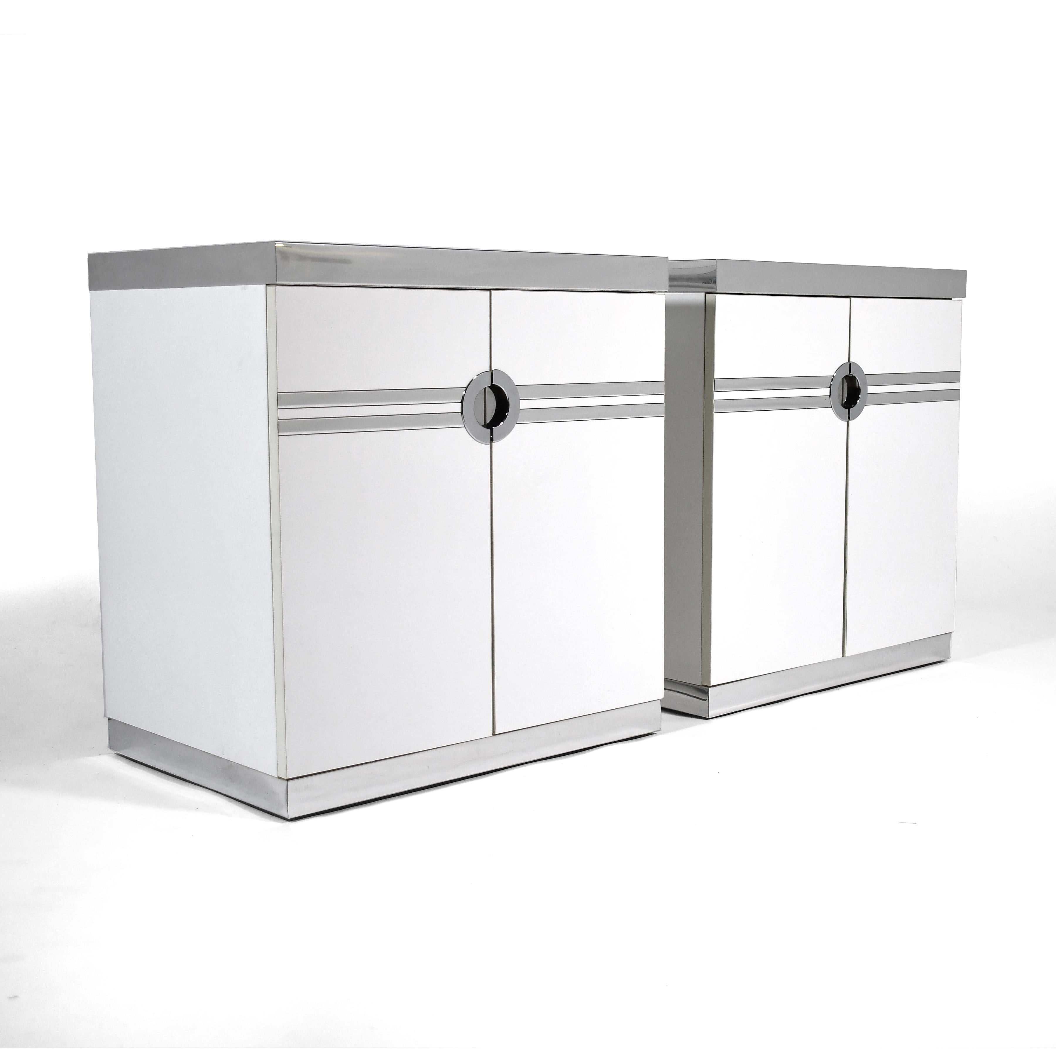 Pierre Cardin's classic aesthetic is on full display with this beautiful pair of nightstands made for the French designer in the US by Dillingham.

The white cases have linear graphic elements and recessed pulls in chrome. The two doors on each