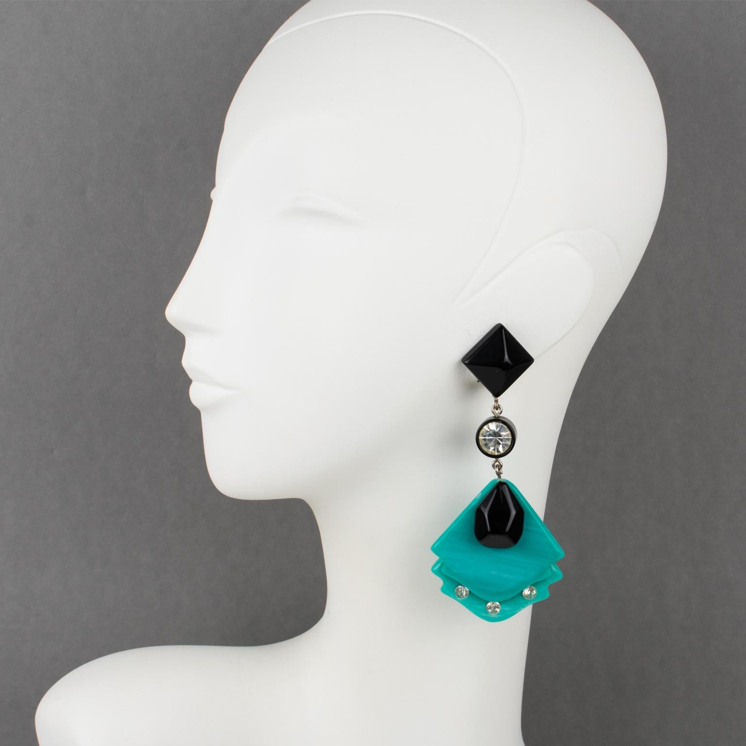 These stunning Pierre Cardin modernist dangling clip-on earrings were designed in the 1970s. The earrings boast a long shoulder-duster geometric shape with black and turquoise resin elements. The earrings have embellishments with crystal