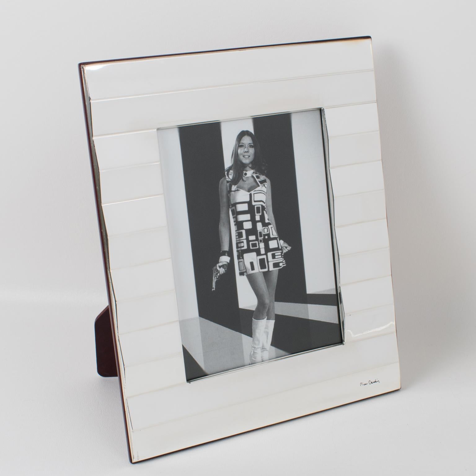 A charming Pierre Cardin (1922 - 2020) Paris silverplate picture photo frame. Geometric shape with a large striped pattern all around. Back and easel in lacquered wood. Engraved on the front is the 
