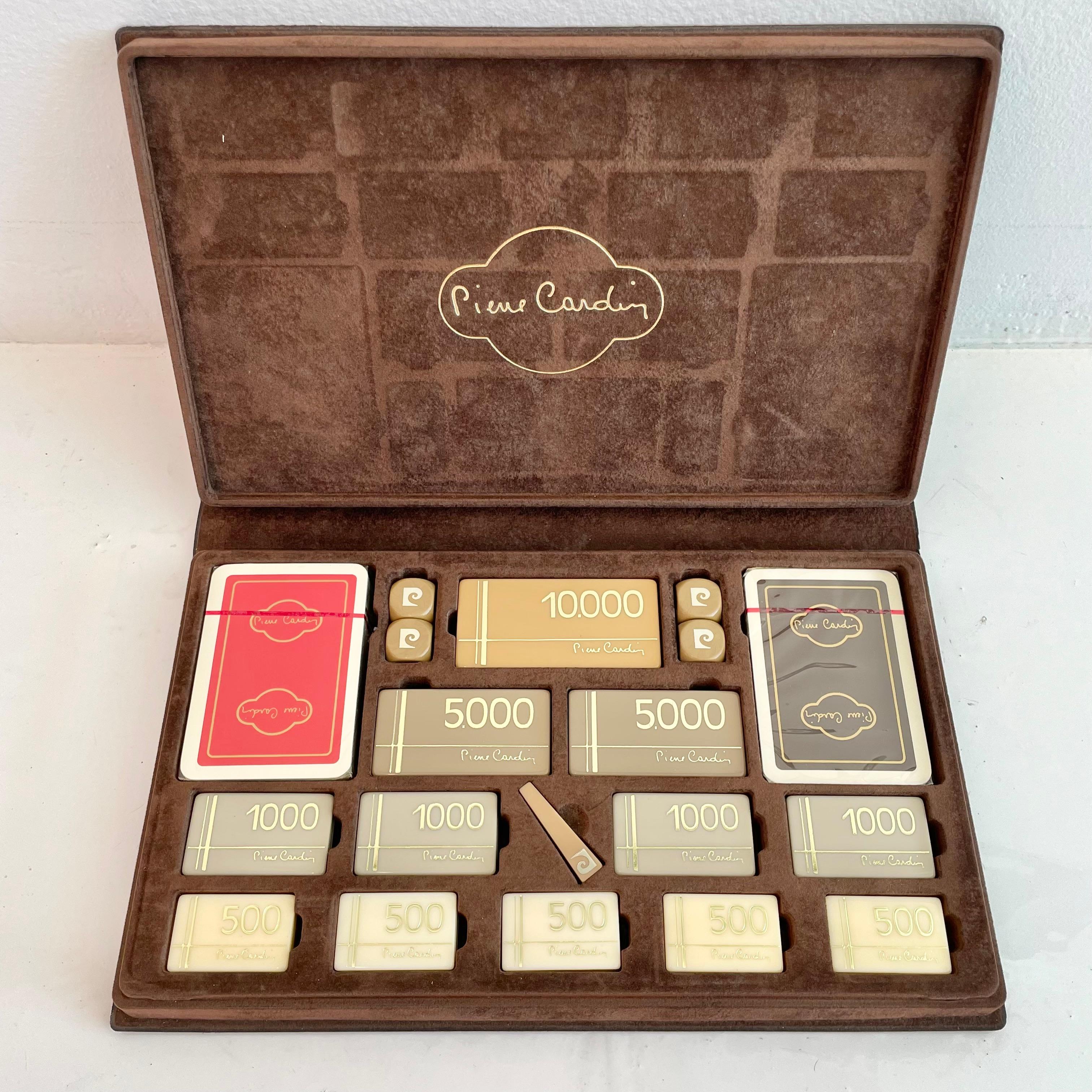 Original and never used, 1970s Pierre Cardin poker set complete with chips (4 x 10,000; 8 x 5,000; 16 x 1,000; 20 x 500), two complete sets of cards and four dice as well as a plastic pic to remove tiles - all in a chocolate brown felt case. Cards