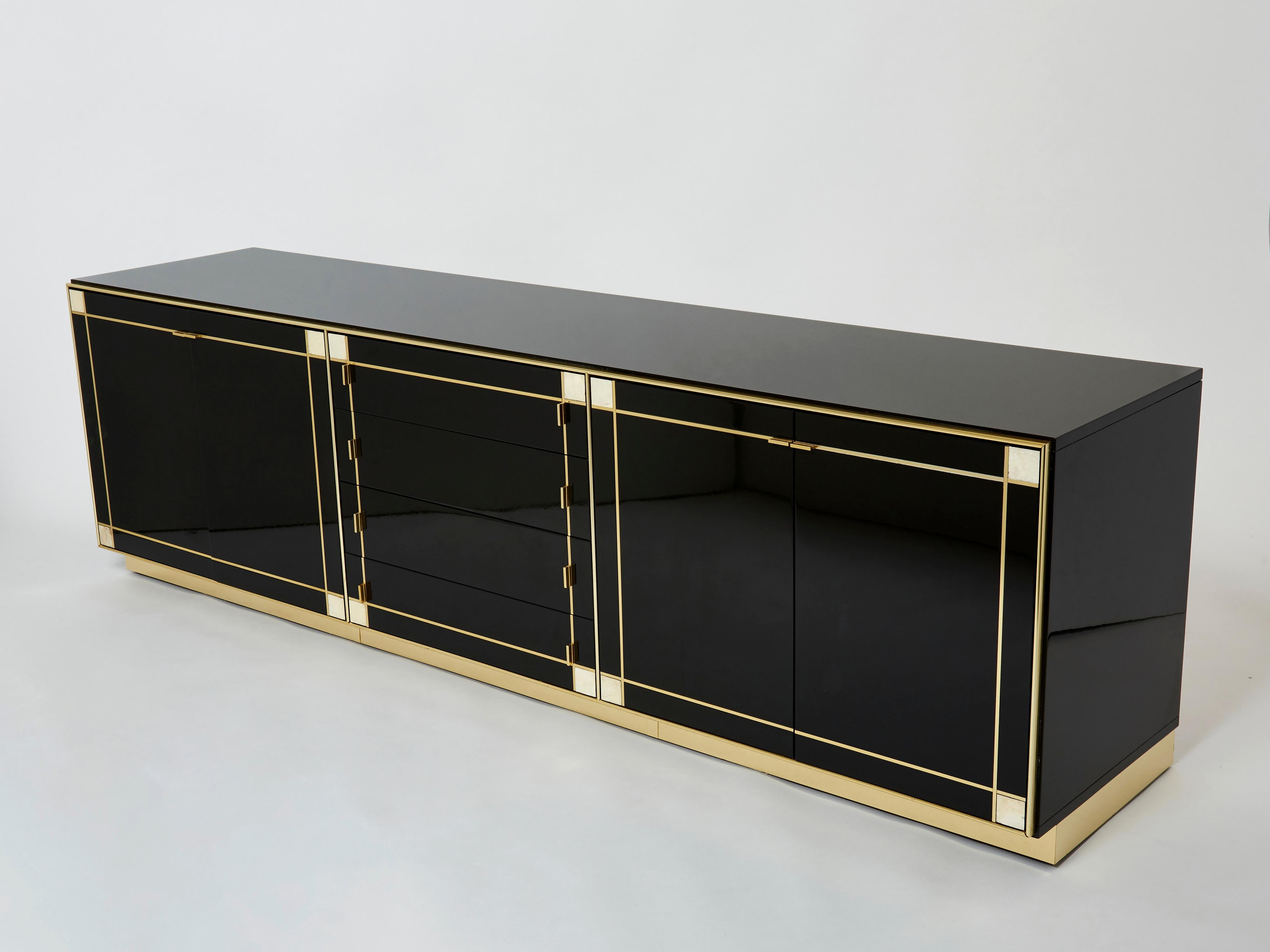 A unique and timeless Pierre Cardin vintage piece, this French midcentury sideboard feels imposing and glamourous, with thick, straight lines of brass adorning its exterior of reflective black lacquer. Glossy black lacquer, paired with bright brass