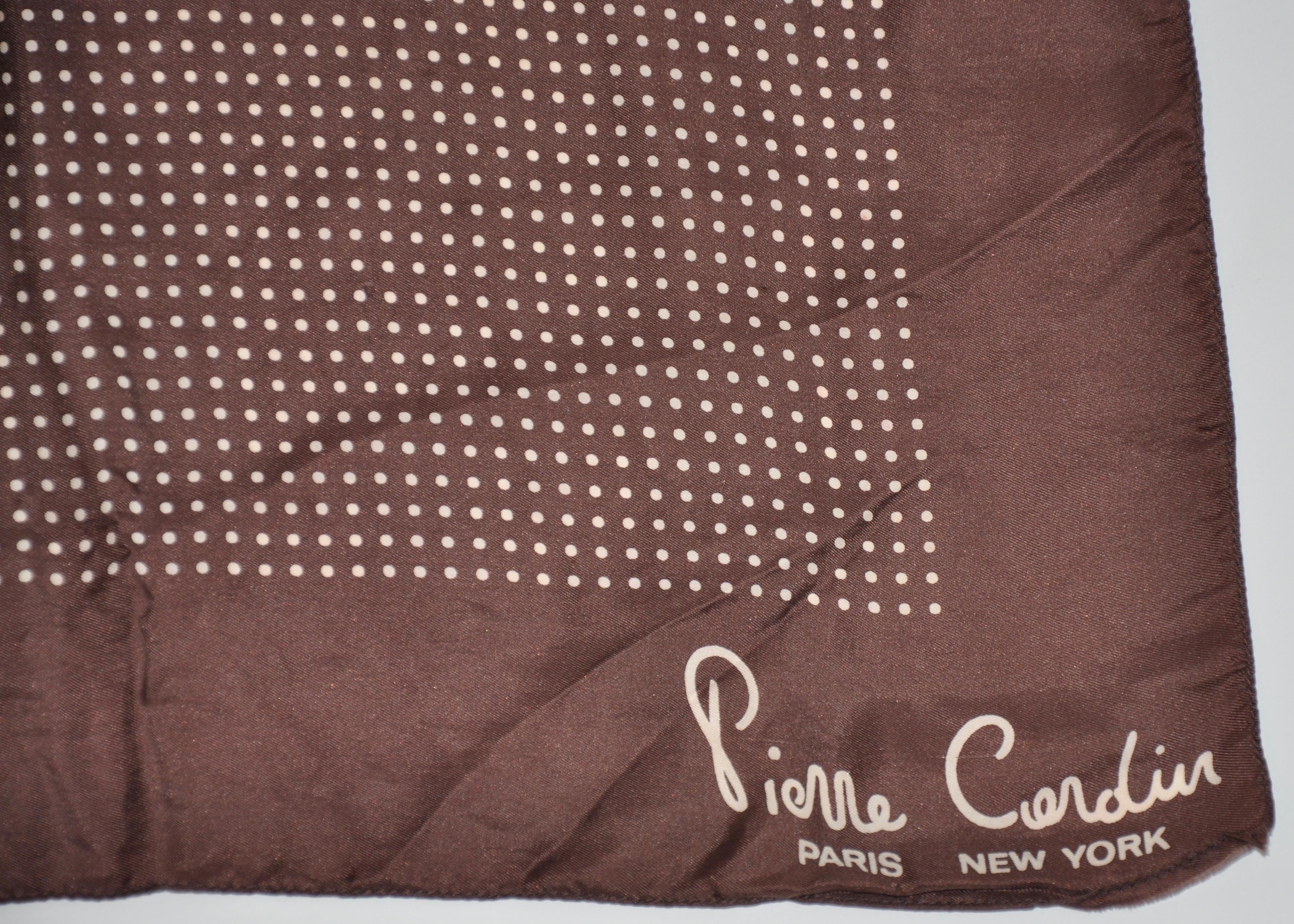        Le mouchoir en soie coco et crème signé Pierre Cardin est accentué par des bords roulés à la main et mesure 17 pouces par 17 pouces. Fabriqué en Angleterre.