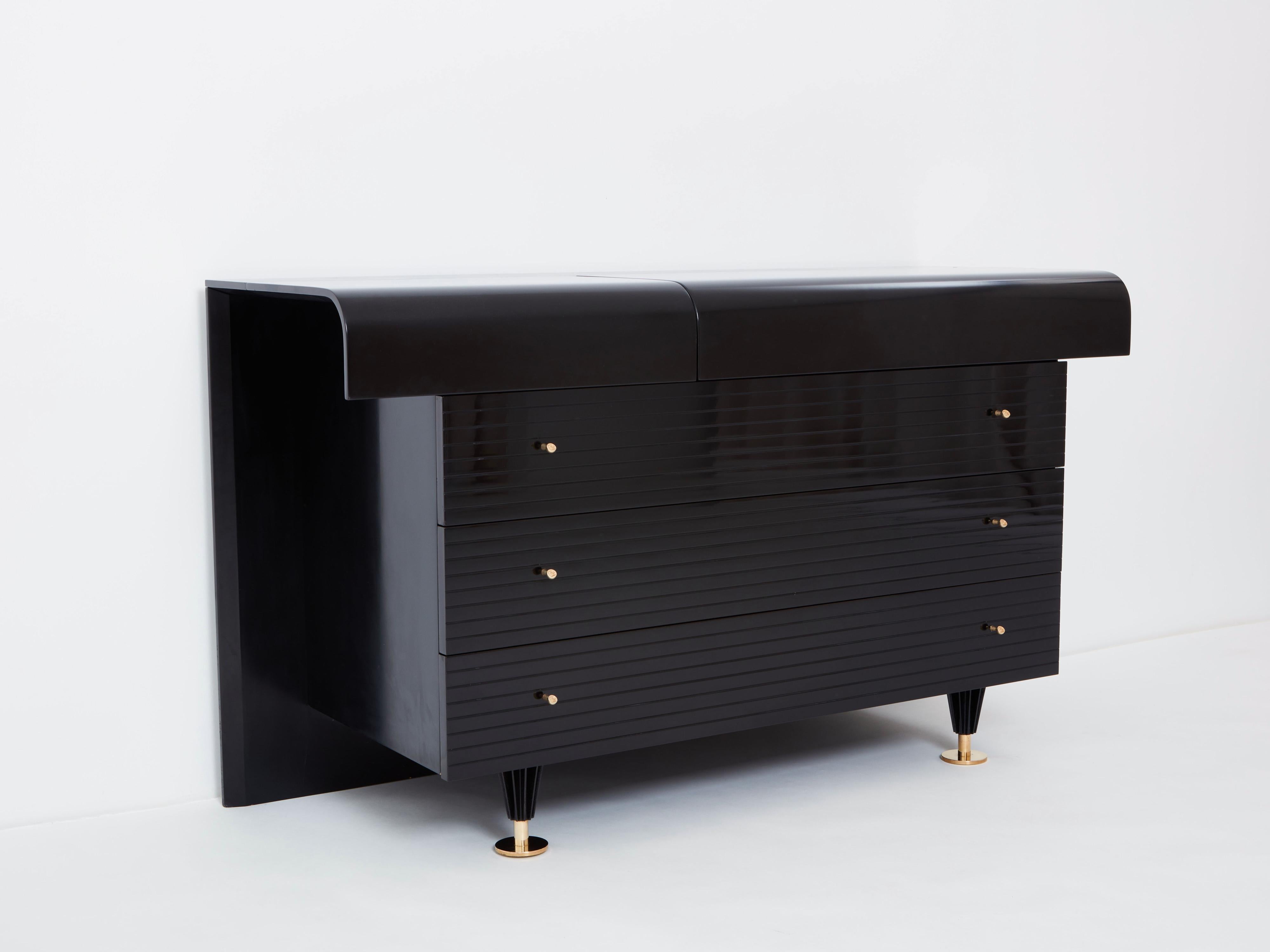 A timeless Pierre Cardin vintage piece made in the 1980s, this French commode feels imposing and glamourous, with a playful mix of straight lines and rounded shape, and brass handles and feet adorning its exterior of reflective black lacquer. Glossy