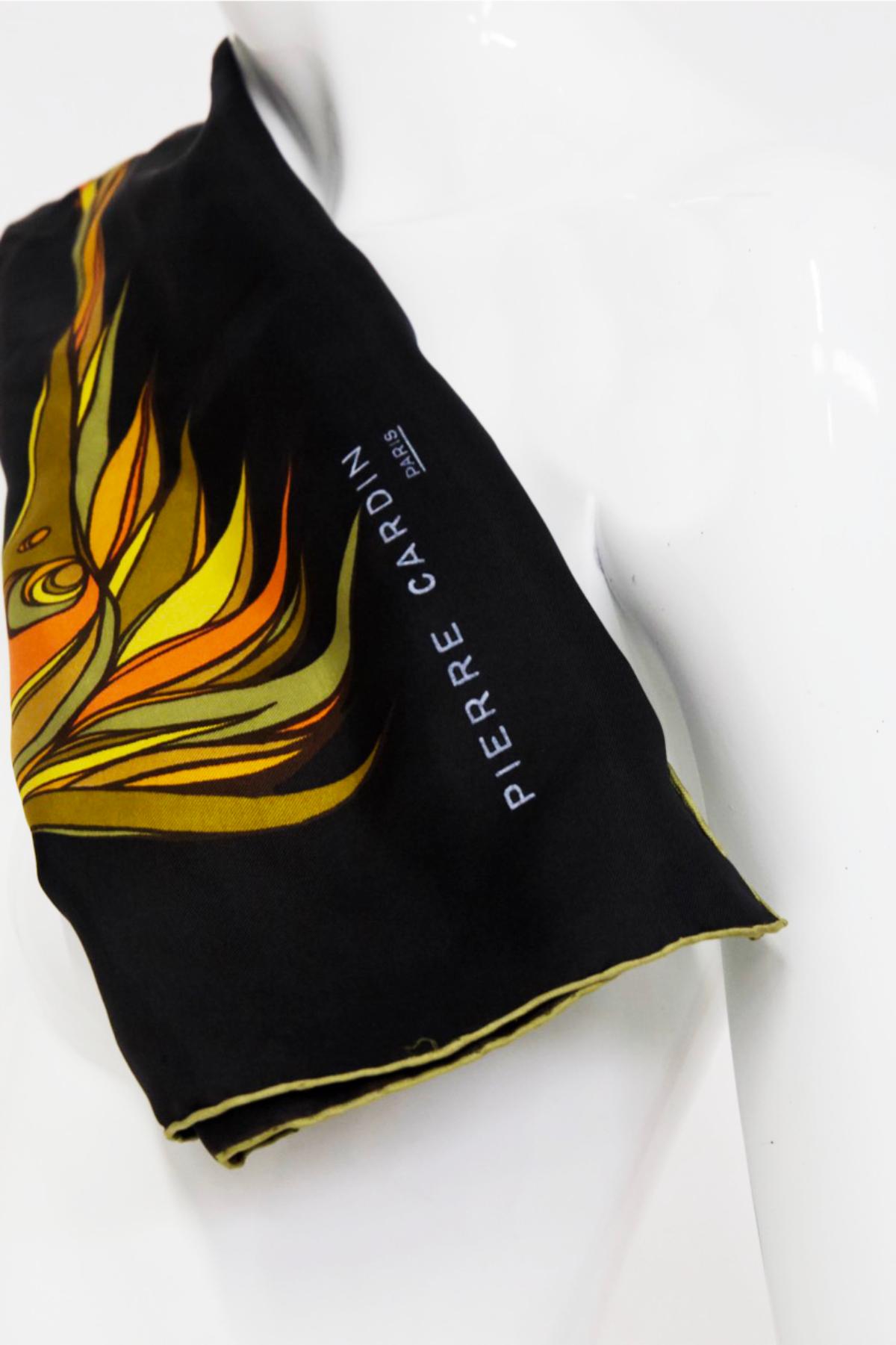 Belle écharpe en satin de soie noire dessinée par Pierre Cardin dans les années 1980, belle fabrication française. SIGNÉ.
Il est entièrement noir, bordé d'or, très élégant. Au centre, outre la signature, on trouve un motif asymétrique coloré en
