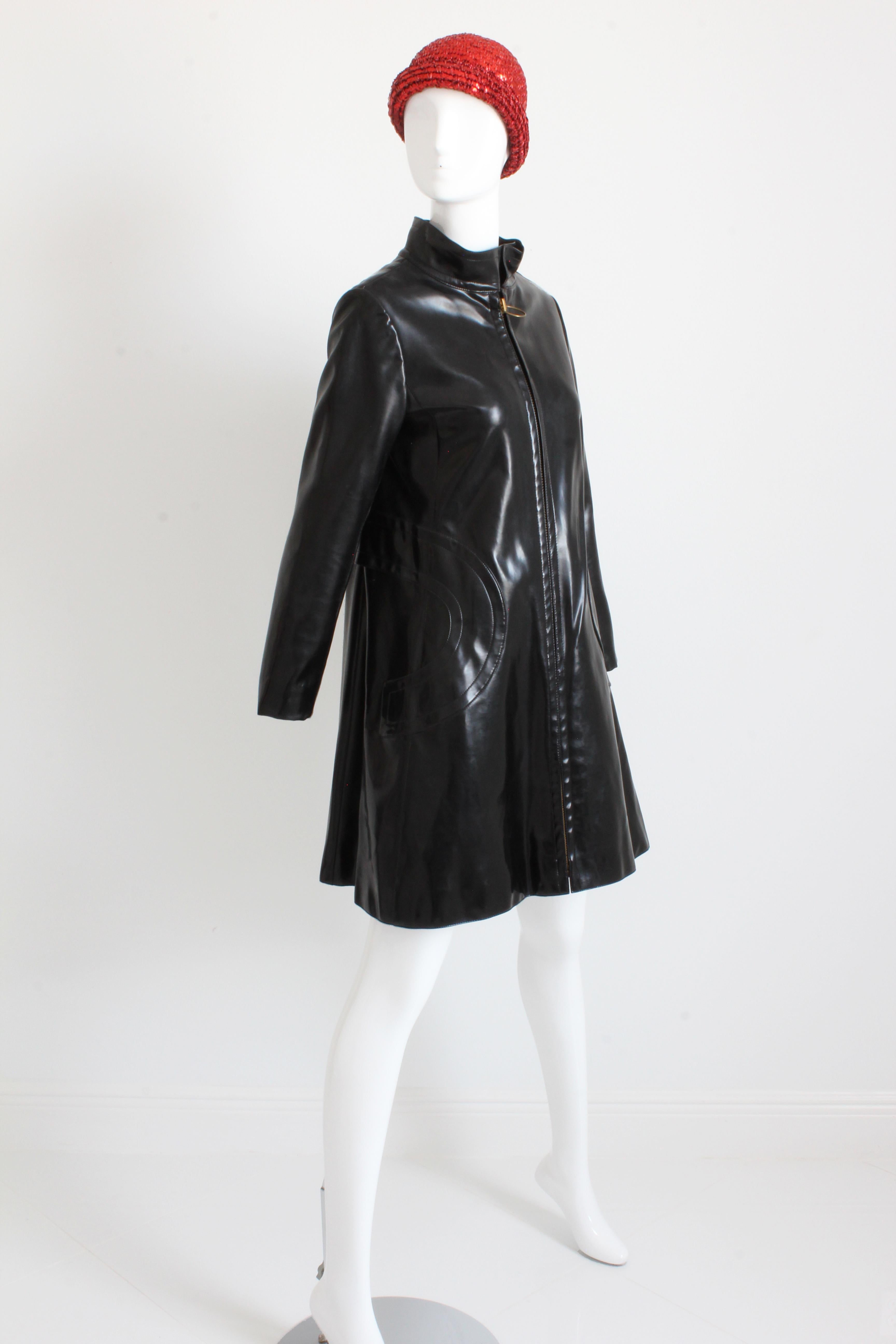 This incredible coat was made by Pierre Cardin for his Space Age and Futurism collection in 1969. Made from black vinyl, it features a mod silhouette with flared hem, a chunky zip front with brass circle pull, and circular stitching trimming the