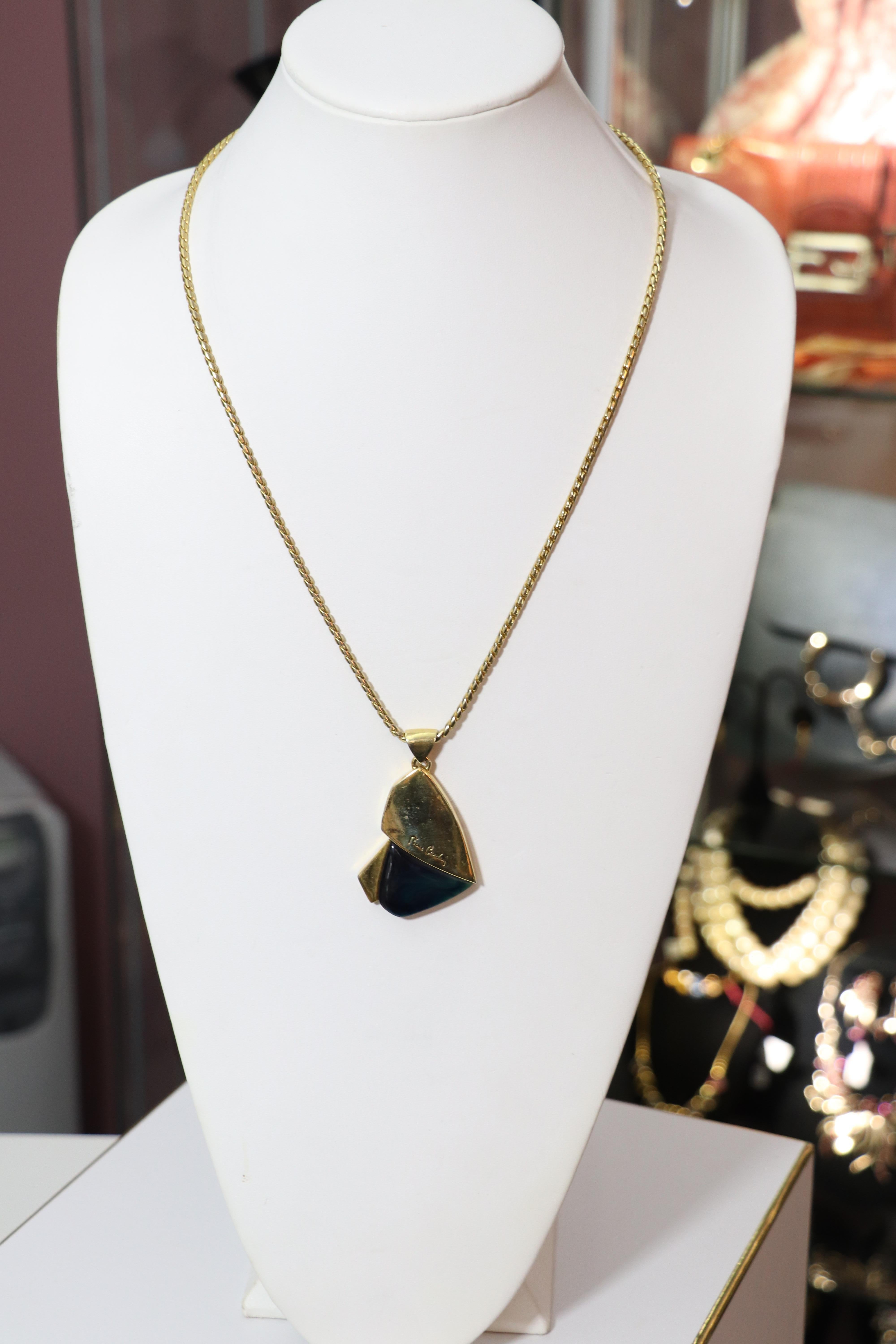 Pierre Cardin modernist pendant necklace features gold-tone hardware with a navy and blue marbled lucite detail and signature. Pendant is on its original chain with a small Pierre Cardin logo motif at the spring ring clasp