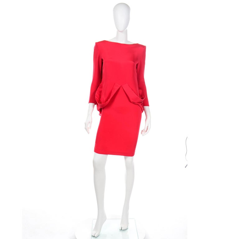 This unique Pierre Cardin vintage red silk crepe dress captures the forward thinking spirit of Pierre Cardin designs. The front is a simple shift dress, with two attached loops of fabric that drape from the waist and along the hips up to the