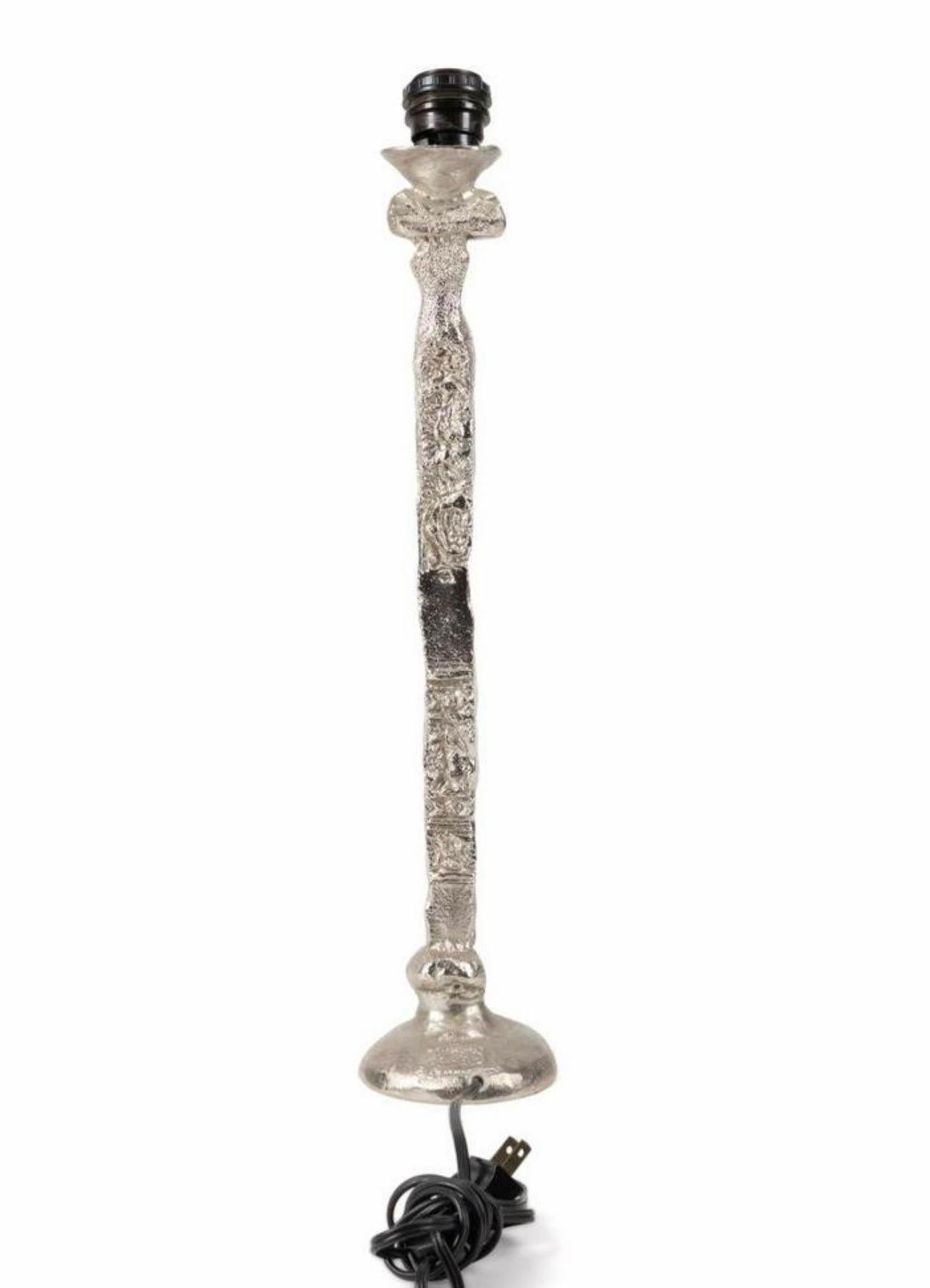 Pierre Casenove (French) 
Silver patina bronze table lamp having a column form and various stamped patterns to the body, stamped signed mark to back of base. 
Approximate dimensions: base h. 21", w. 5" X 5".
This is a bit more rare as most of his