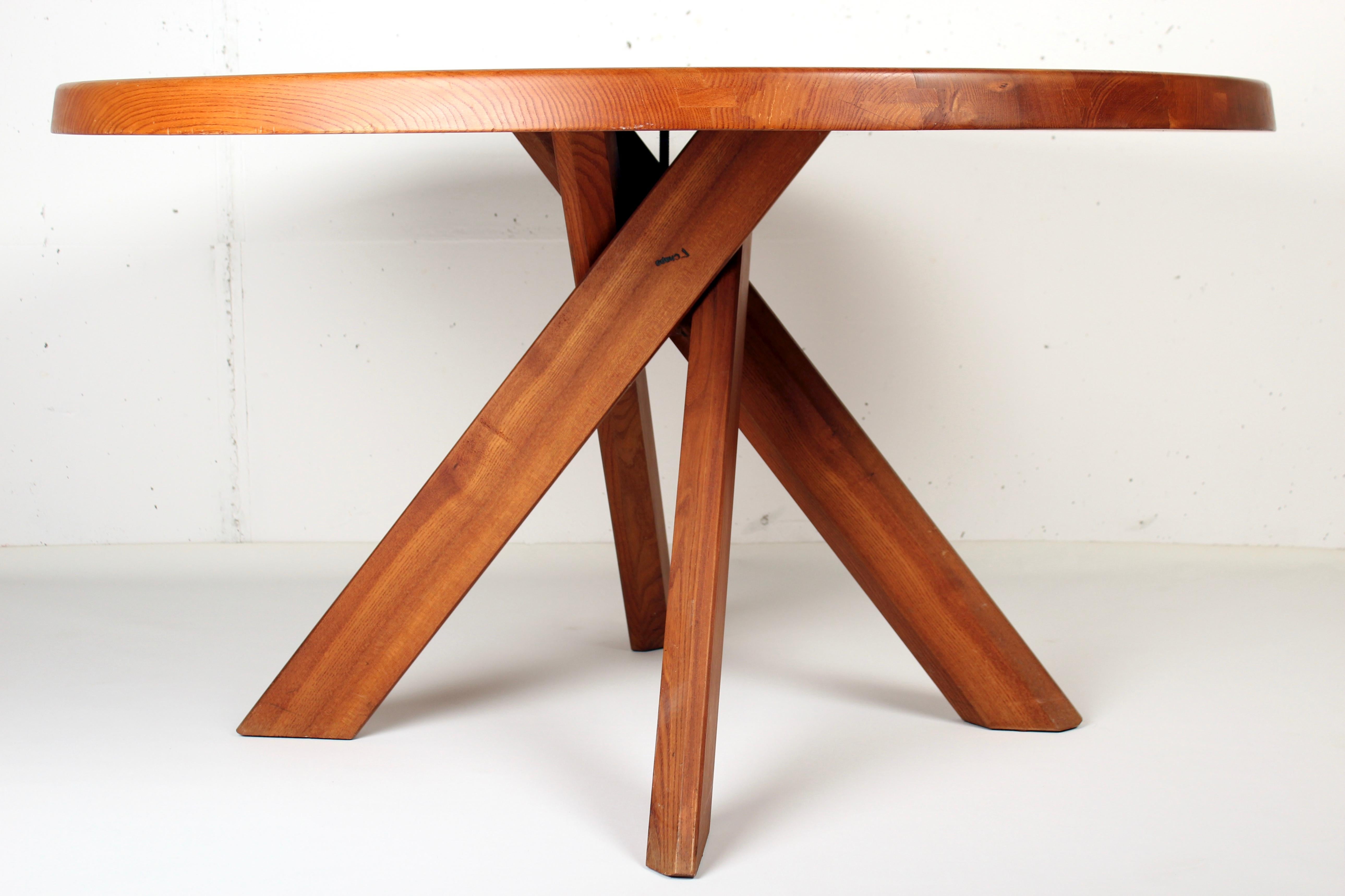 Cette table est dans un bel état patiné. La forme de la base crée un aspect très ouvert et en fait un objet qui rend l'espace plus intéressant. Le plateau rond a magnifiquement exposé les veines du bois d'orme, ce qui confère à cette table un